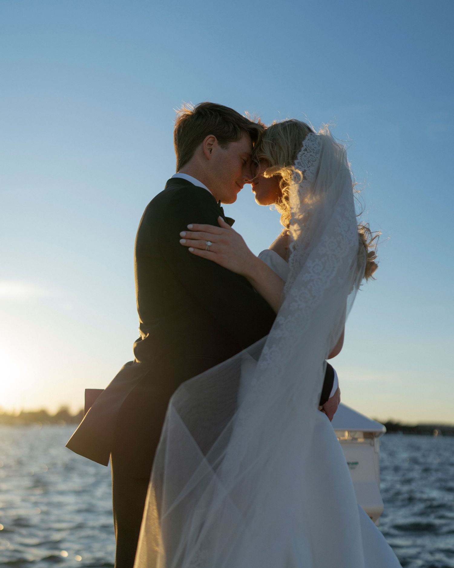 Newlyweds share an intimate moment at sunset with the ocean as their backdrop.