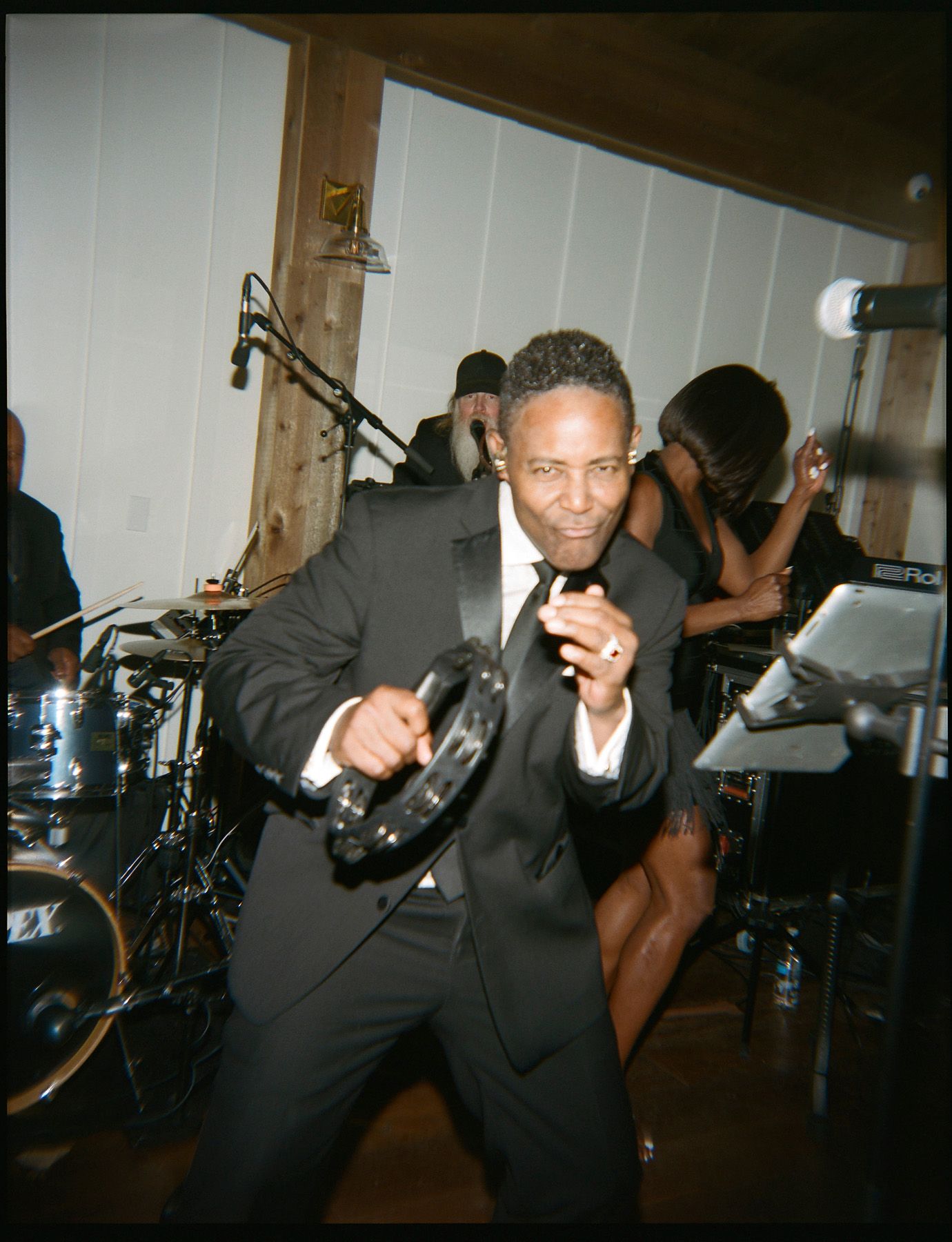 Partygoers in formal attire dance enthusiastically in a dimly lit venue.