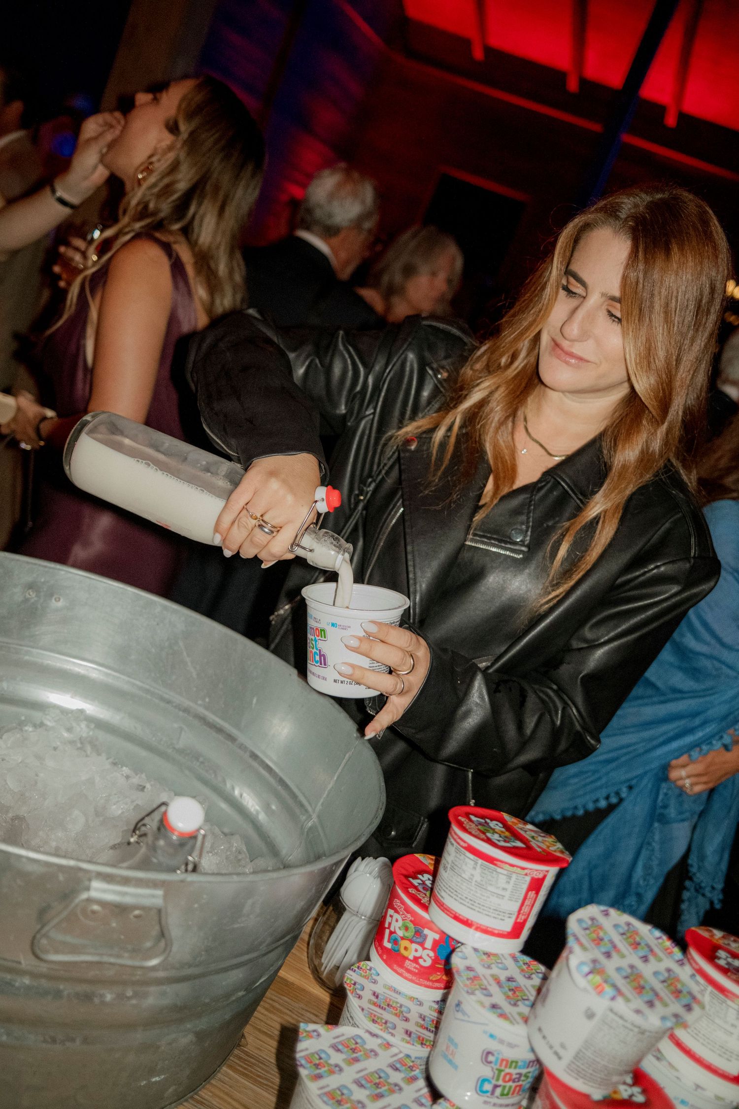 Party scene with ice buckets and drinks being served under red ambient lighting.