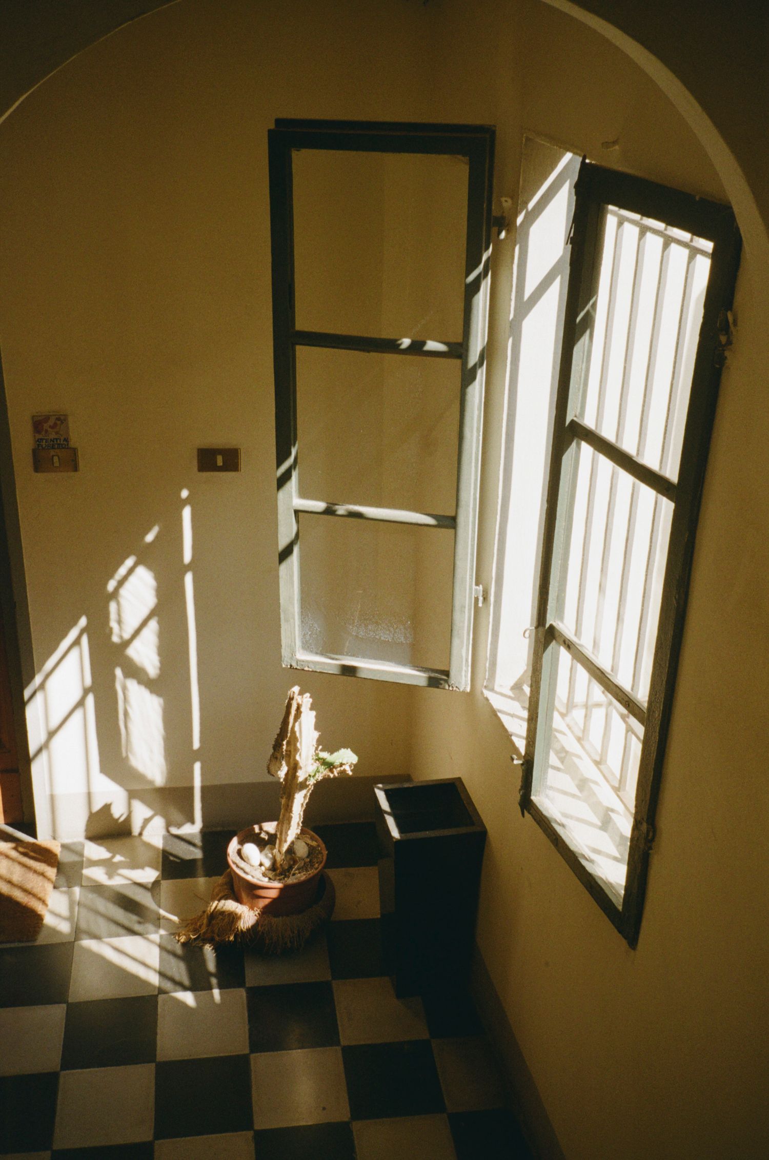 Sunlight streaming through windows creating geometric shadows on a checkered floor.