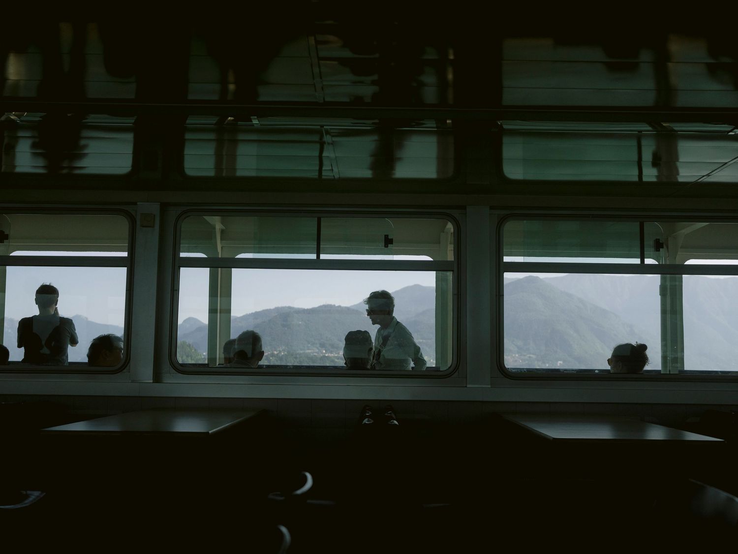 Silhouette of a bus or train interior against a mountain backdrop at dusk.