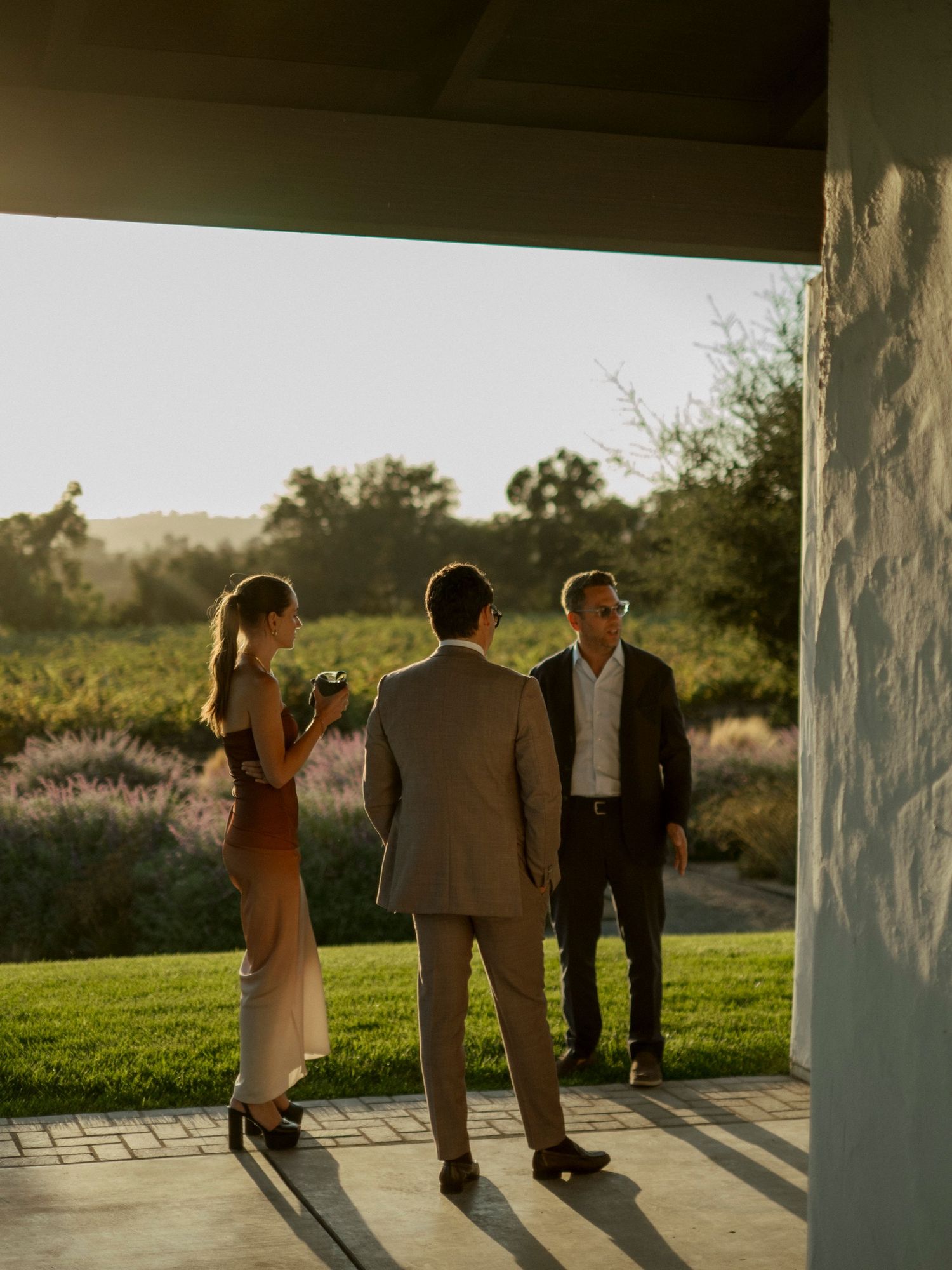 Silhouettes of wedding guests walking together at sunset against a scenic backdrop.