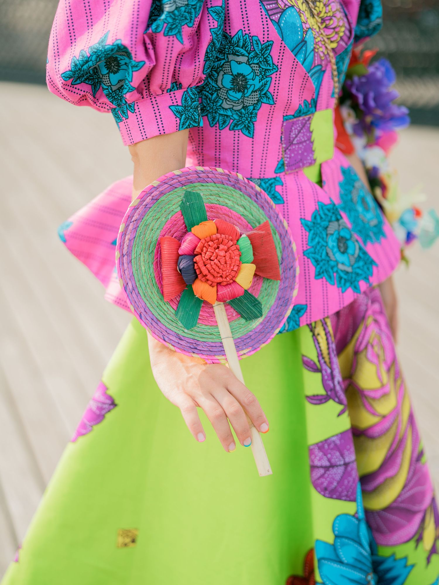 Detailed view of bright pink and turquoise floral patterns on a lime green dress.