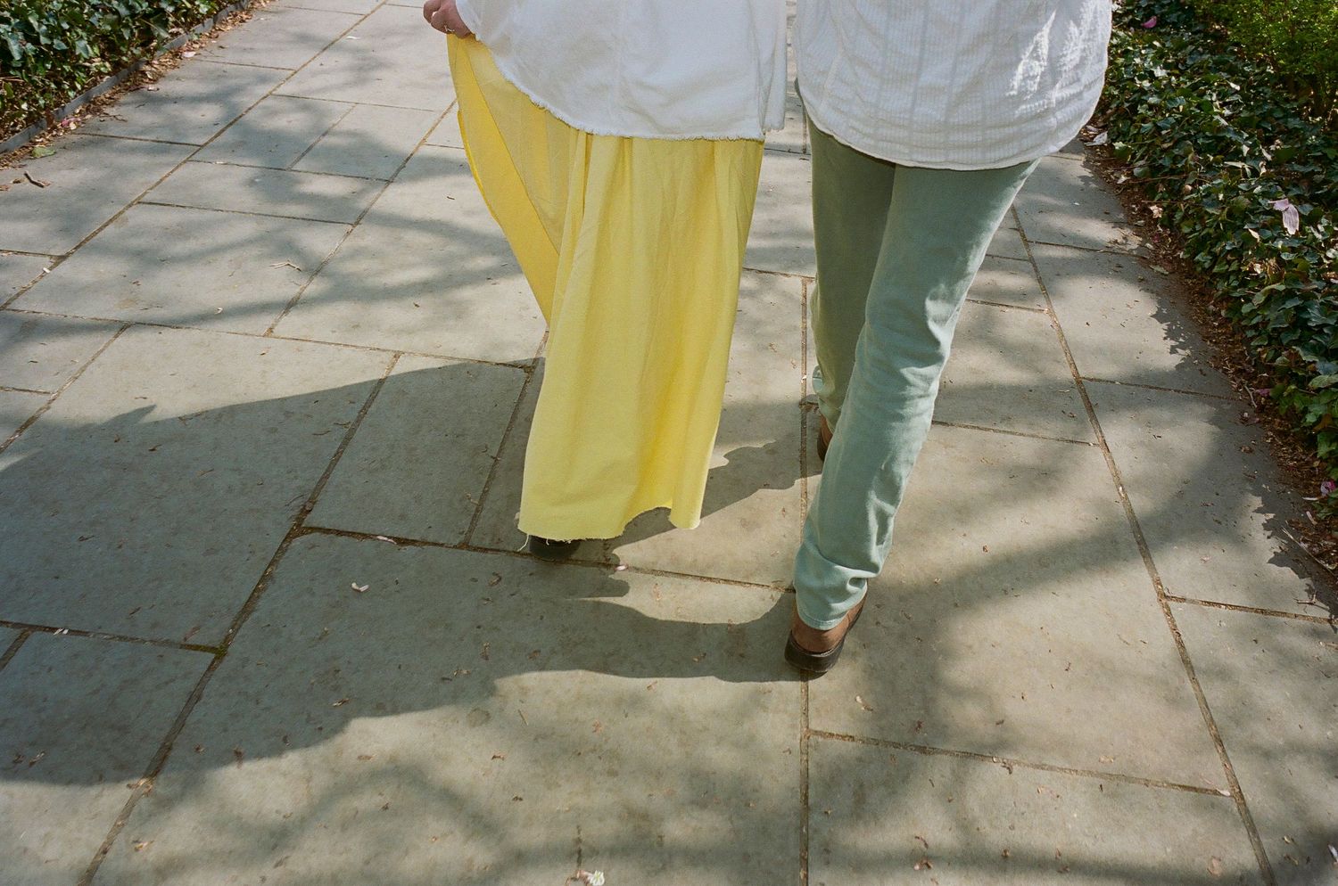 People walking on a stone pathway surrounded by spring greenery.