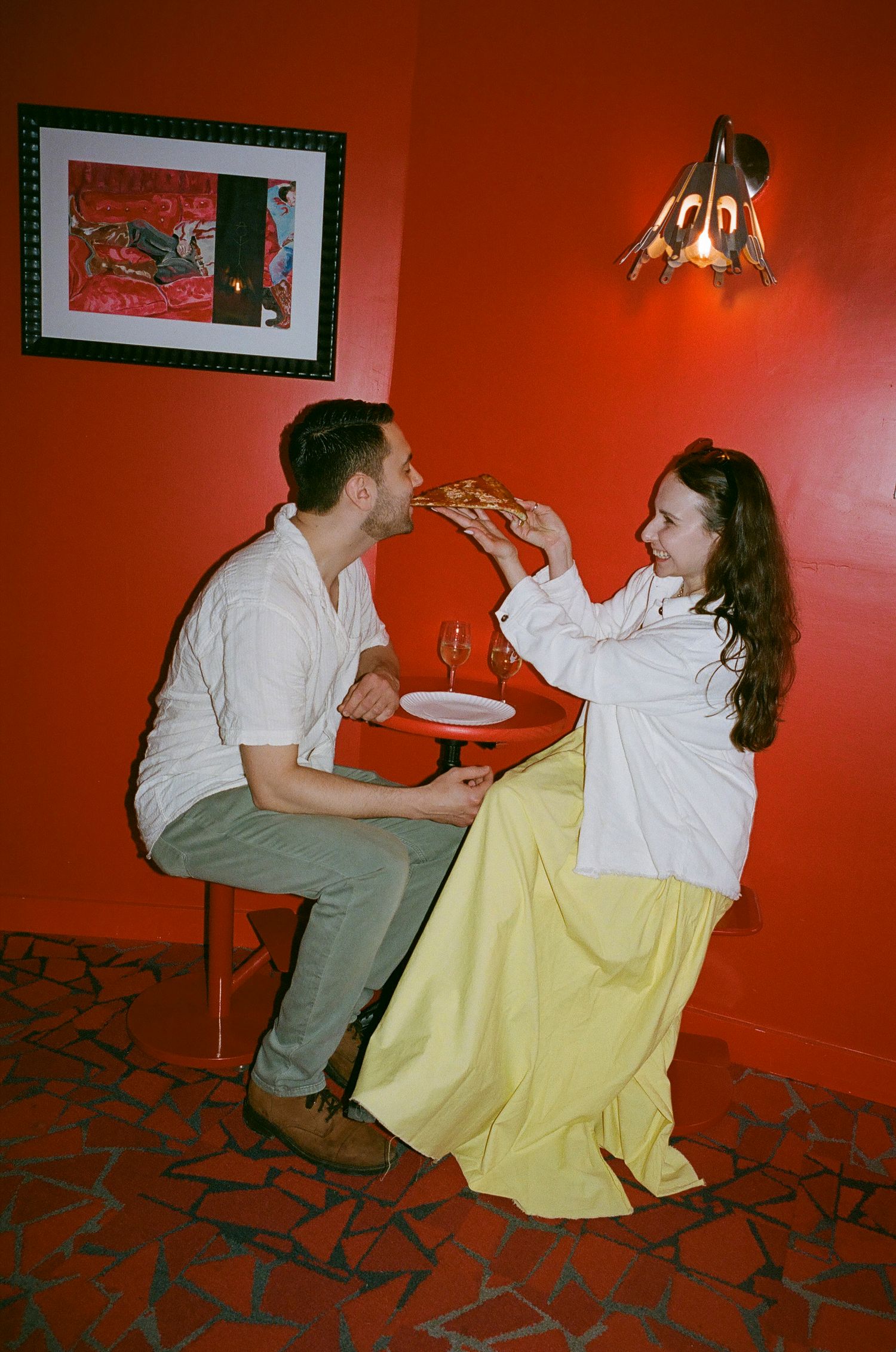 People sitting against a red wall having drinks and conversation.