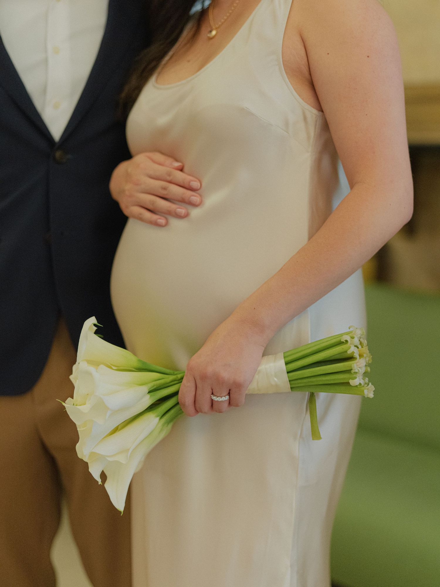 A close-up shot of a bouquet of white calla lilies held against a flowing white dress.