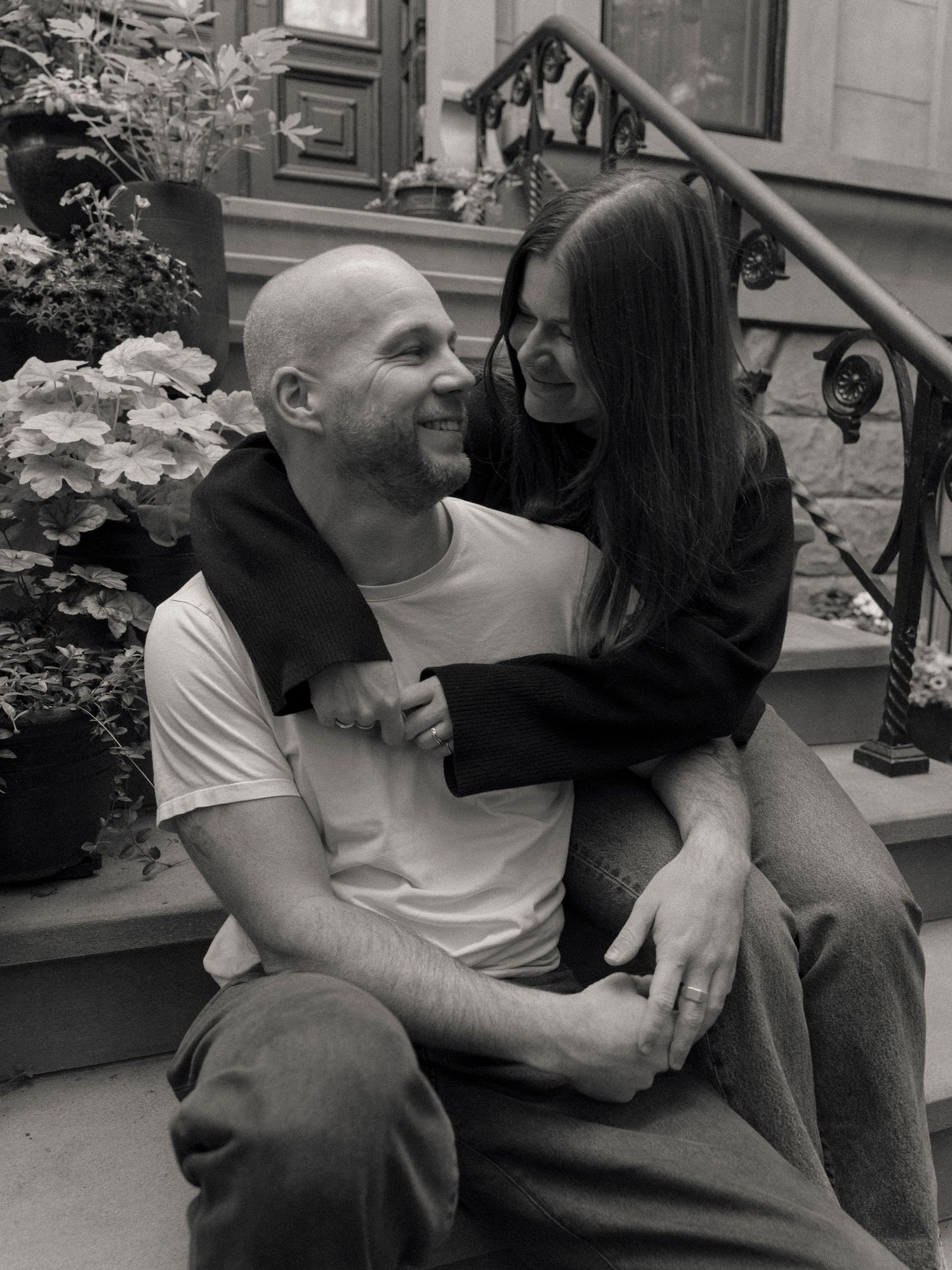A couple shares a tender moment on brownstone steps with hydrangeas nearby.