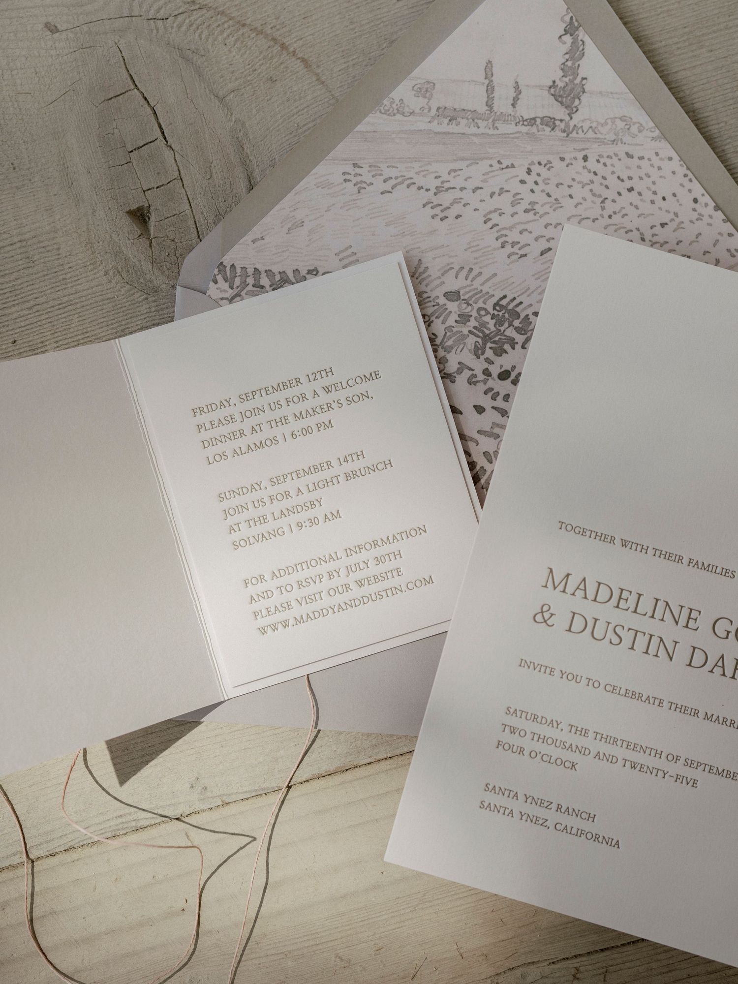 Elegant white wedding invitations with classic typography laid out on a textured surface.