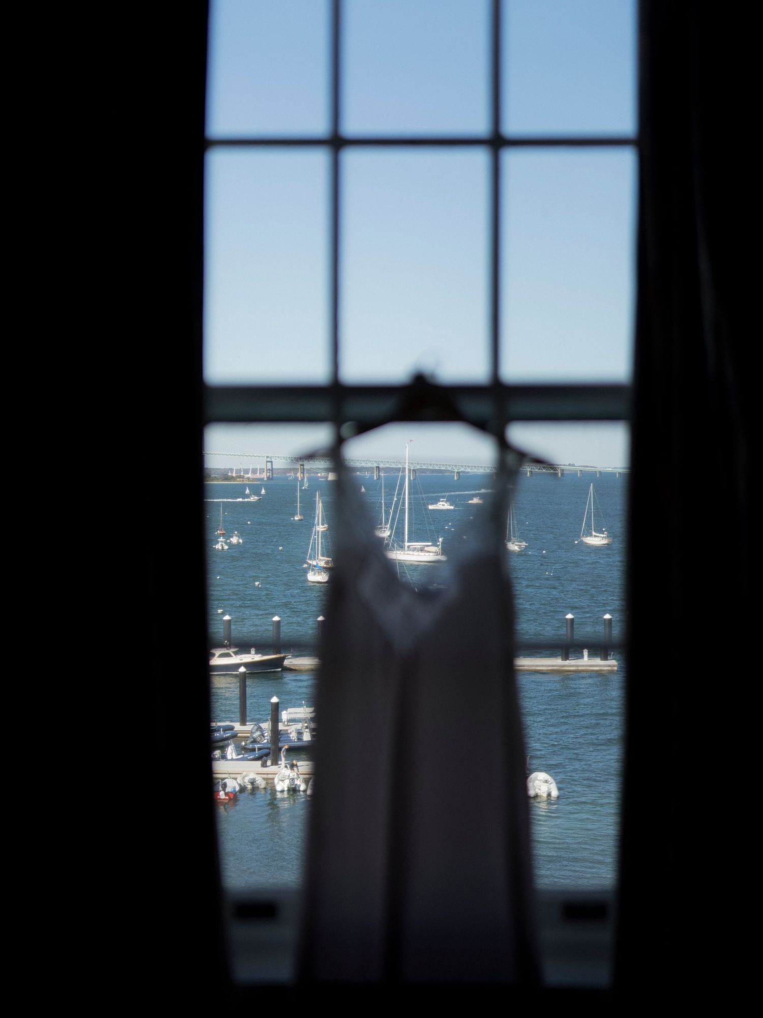 Sailboats anchored in harbor viewed through window silhouette.