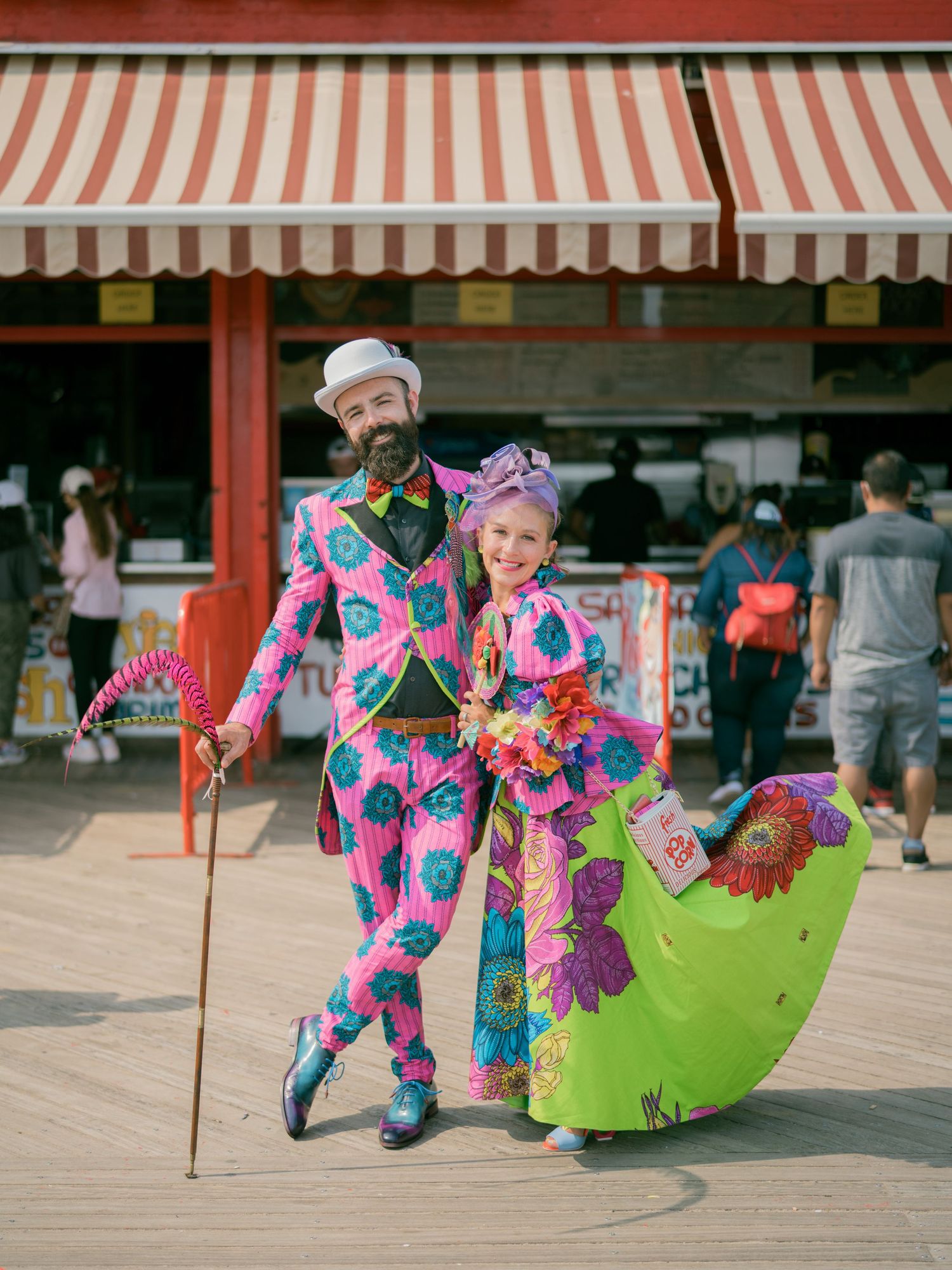 A playful dance sequence on a boardwalk under red and white striped awnings.