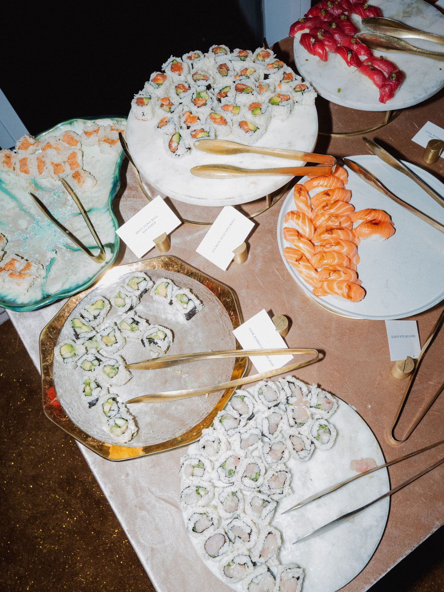 Various platters of sushi and seafood appetizers arranged on a catering table.