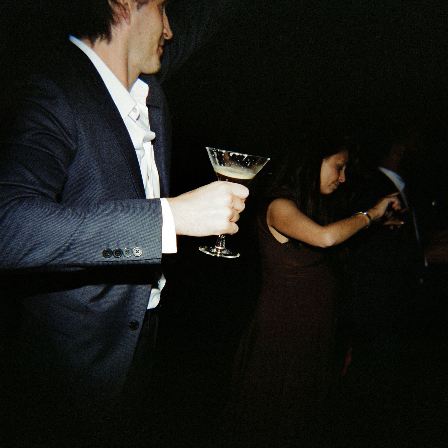 Dark atmospheric shots of guests mingling at a nighttime wedding reception.