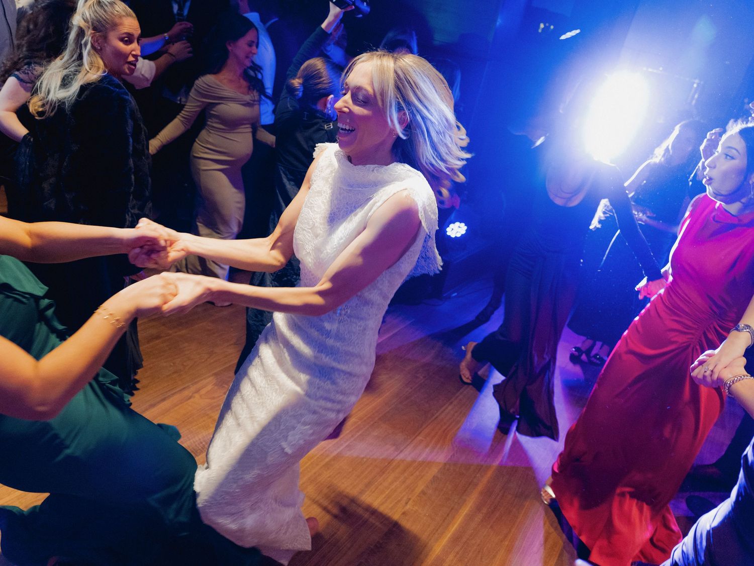 Wedding reception dance floor with blue lighting and guests celebrating.