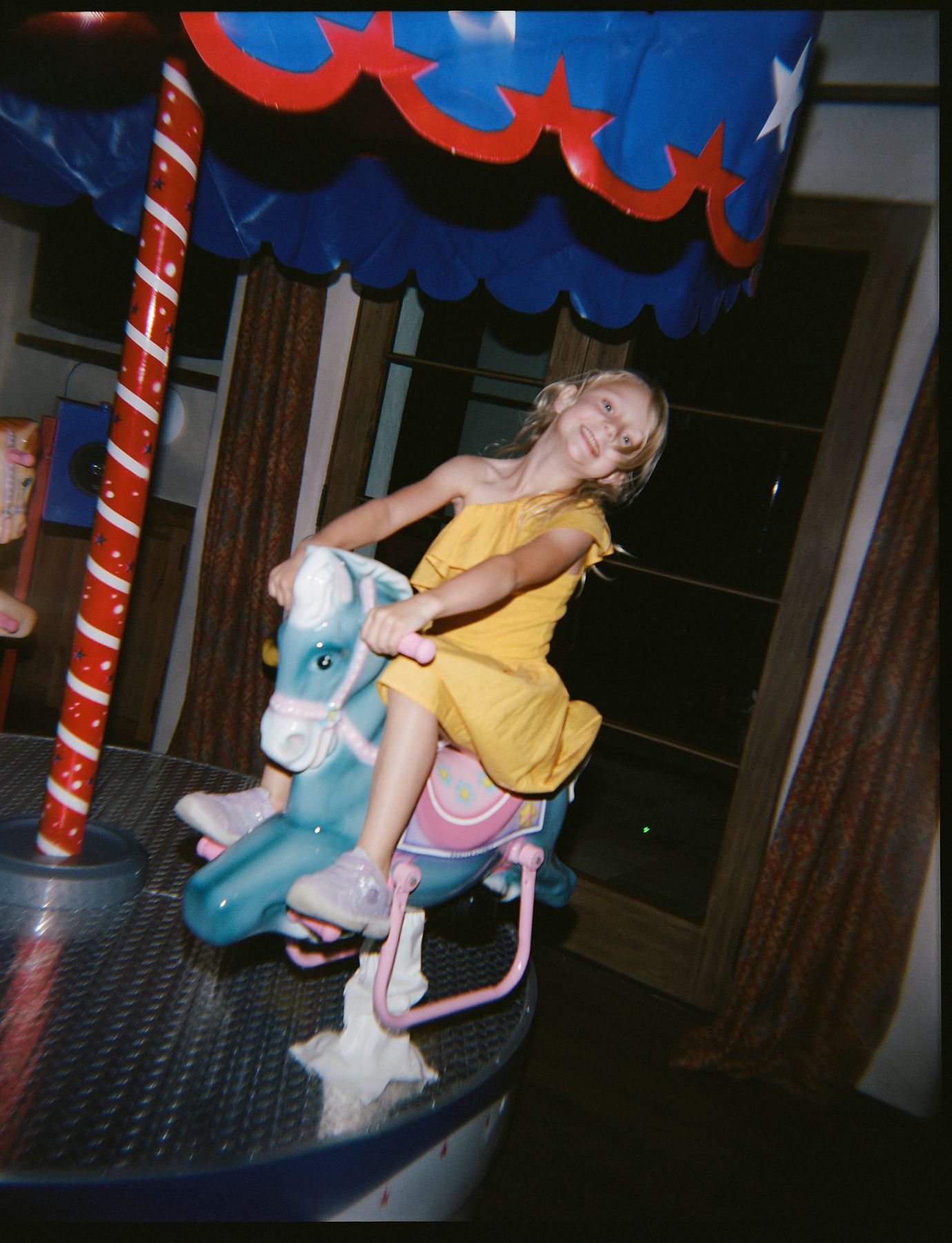 Person in yellow shirt riding a carousel horse at an amusement park.