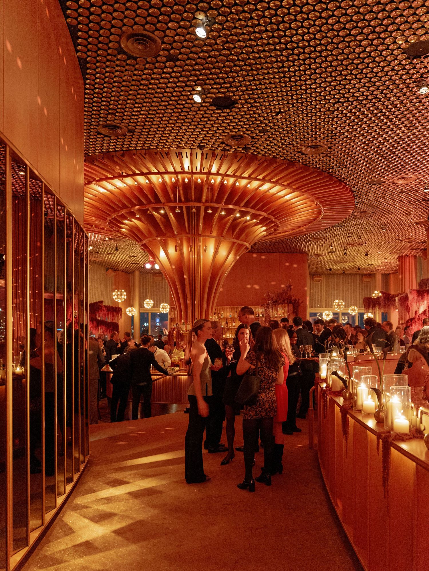 A luxurious event space with honeycomb ceiling design and dramatic amber lighting.