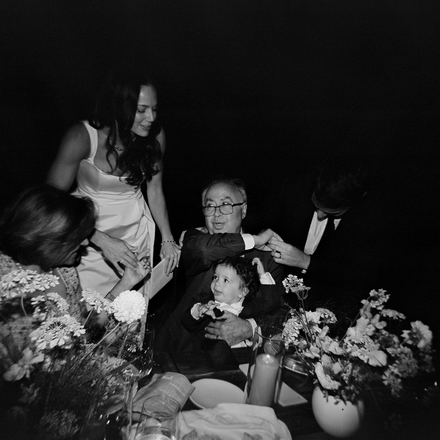 Black and white photo of a wedding reception table with floral arrangements.