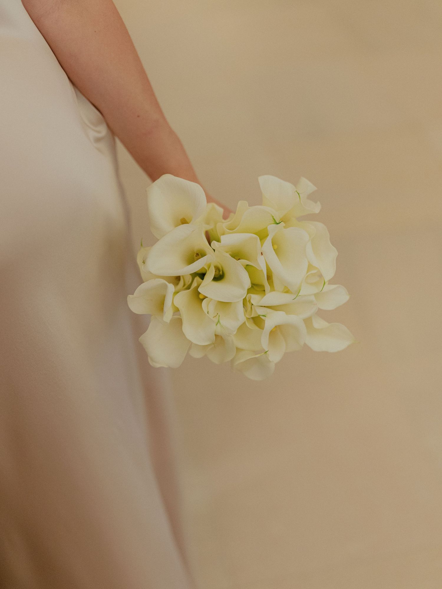 Close-up shots of delicate white calla lily flowers against a beige background.