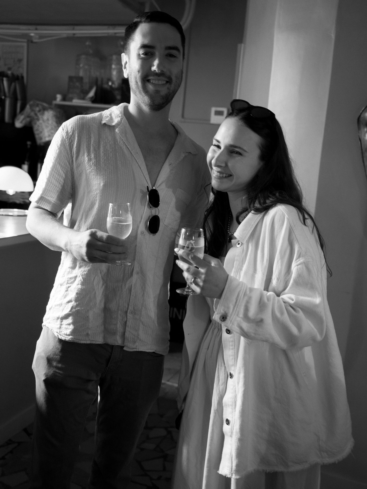 Group enjoying drinks and conversation at indoor gathering in black and white.