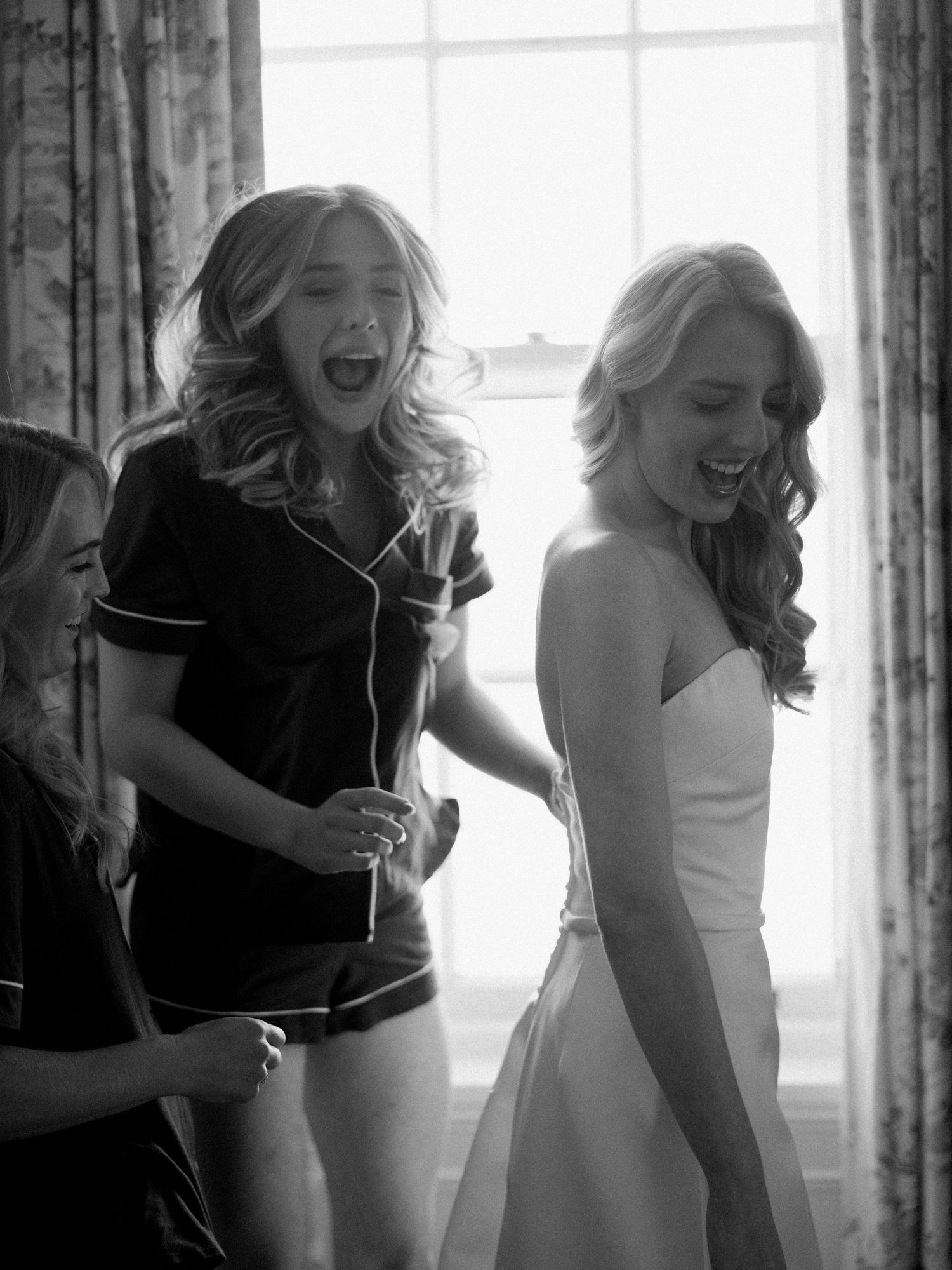 Women in formal attire laughing together during a special occasion.