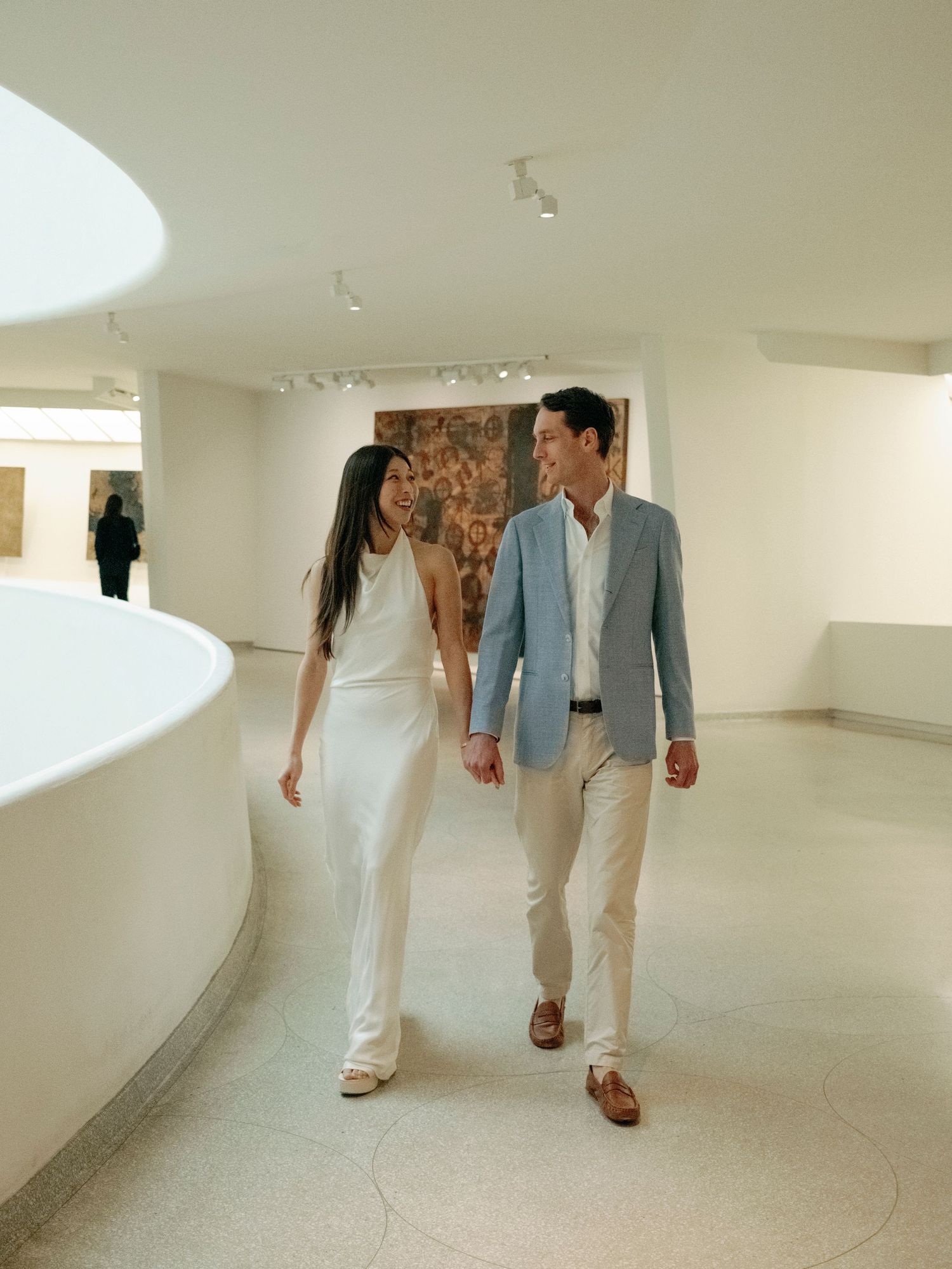 People walking through a modern white gallery space with curved walls.