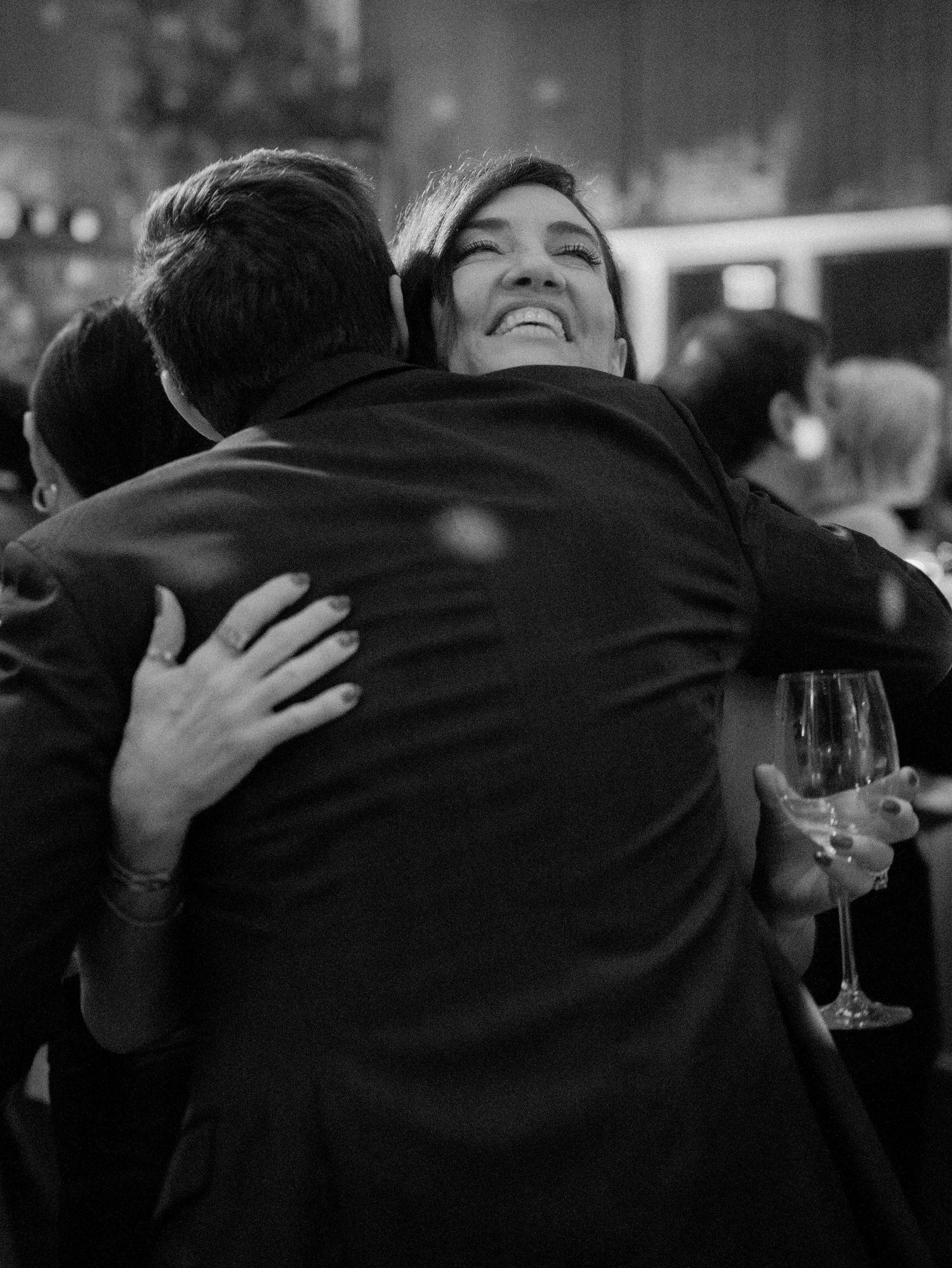 Warm embrace at an evening celebration with champagne glass in hand.