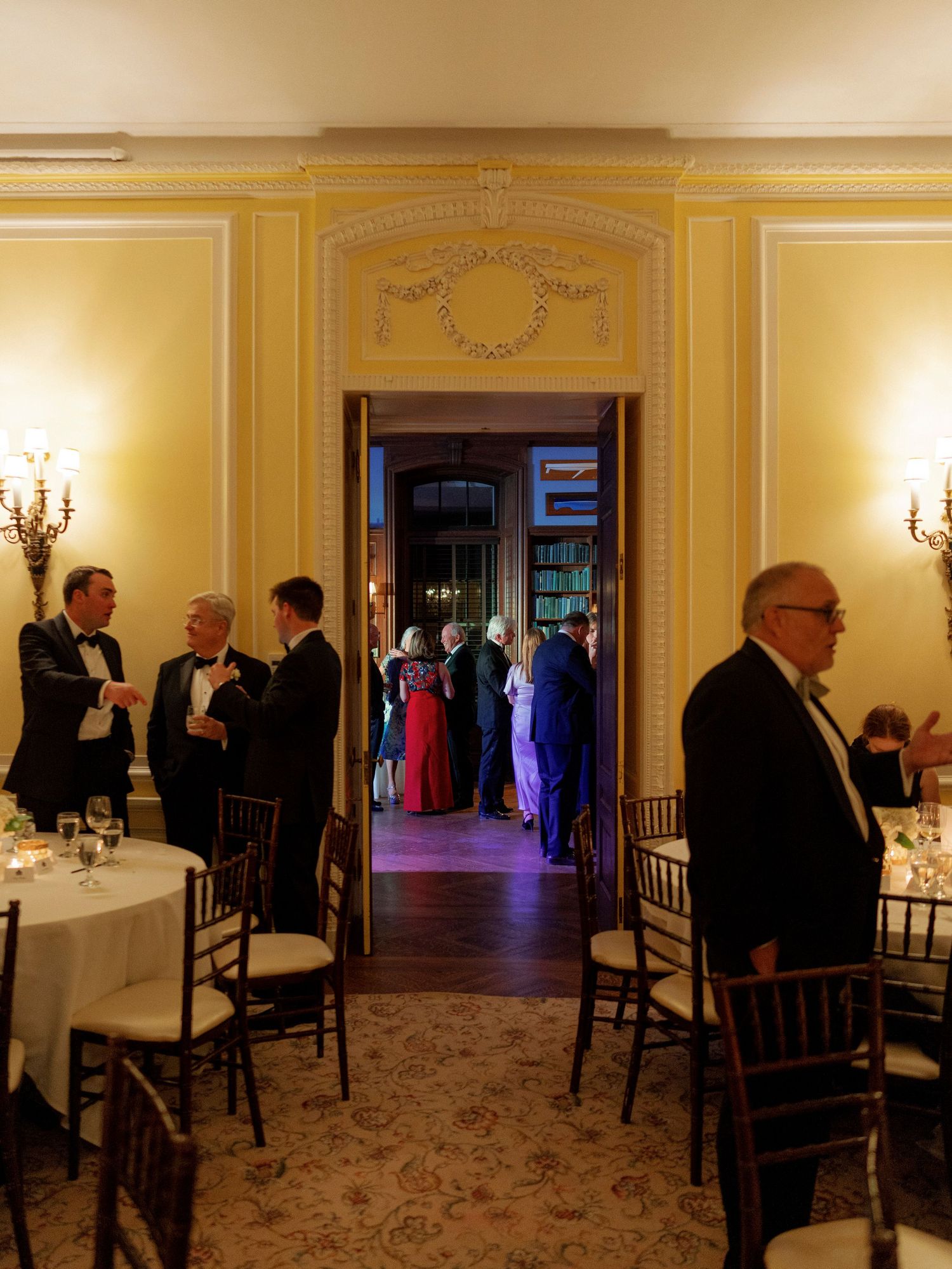 Panoramic view of an elegant yellow ballroom with chandeliers and formal dining setup.