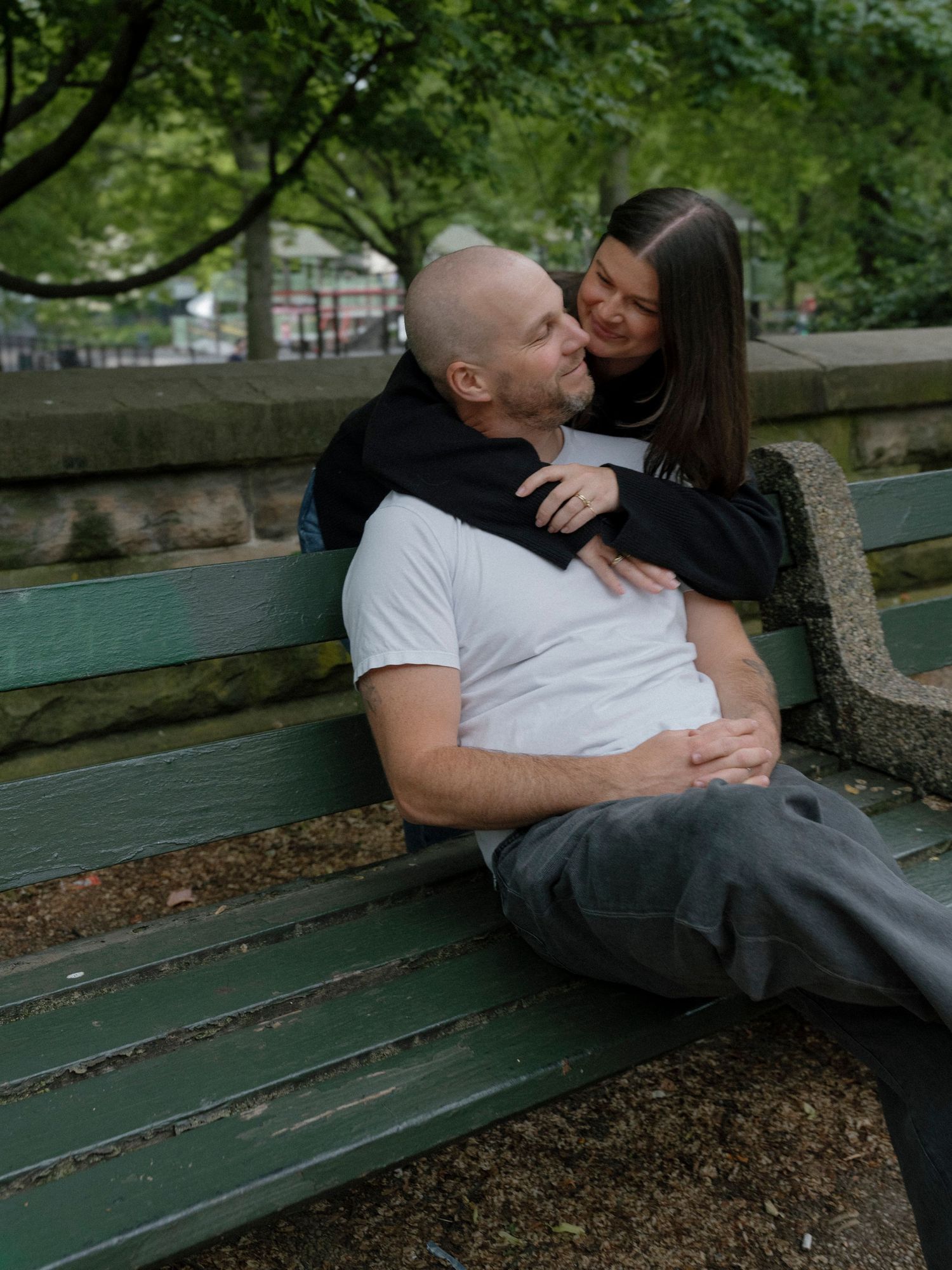 Couple sharing an intimate moment on a park bench surrounded by greenery.