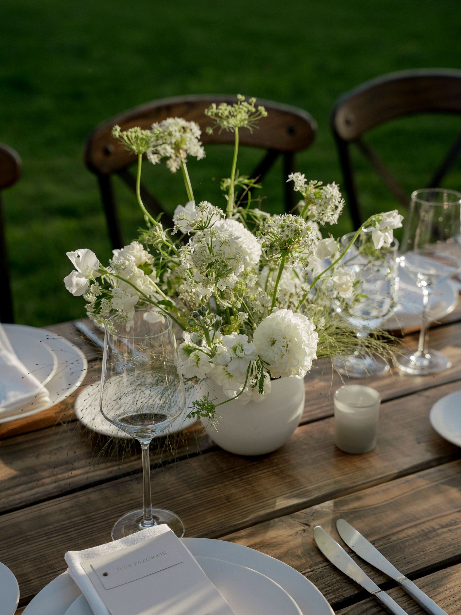 Delicate white floral centerpiece with Queen Anne's lace in rustic outdoor table setting.