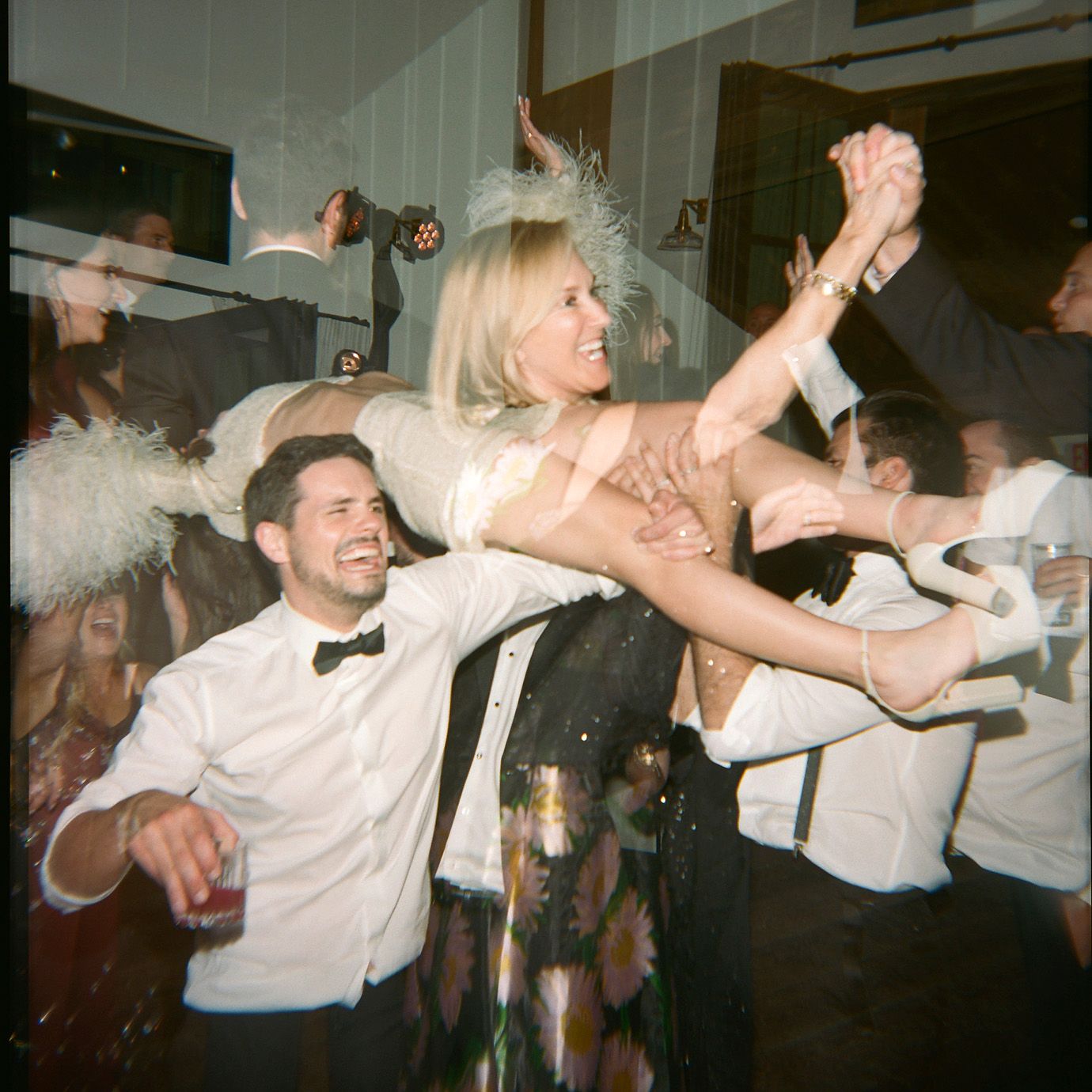 Wedding guests dance and celebrate energetically on a crowded dance floor at a reception party.
