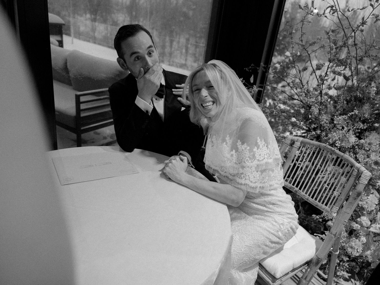 Intimate black and white wedding photography session showing couple in romantic poses with floral arrangements.