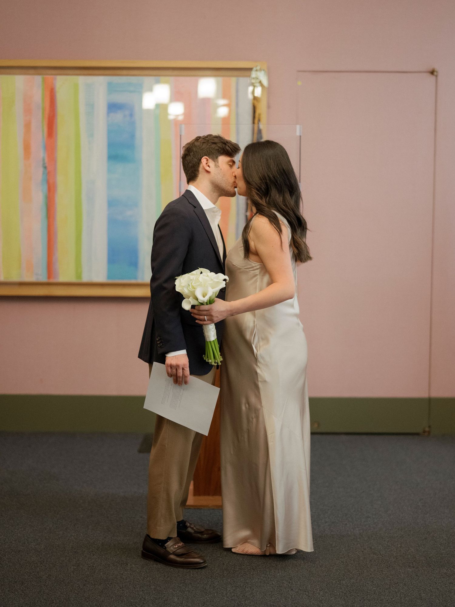 A series of romantic moments captured in a pink-walled room with striped artwork.