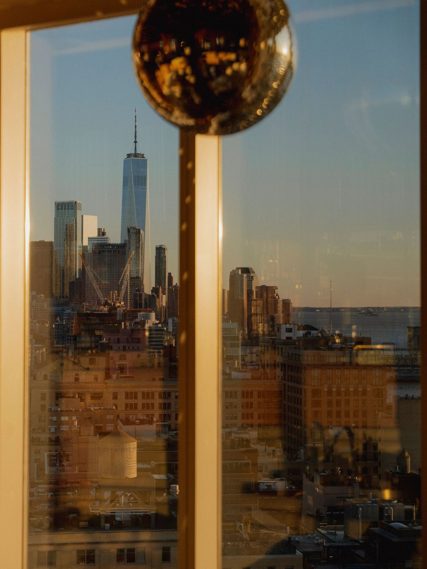 Golden hour cityscape view through large windows with decorative spherical ornaments.