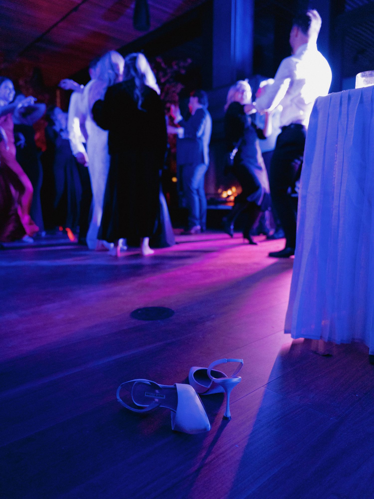 Dance floor at a wedding reception illuminated by purple and blue lighting.
