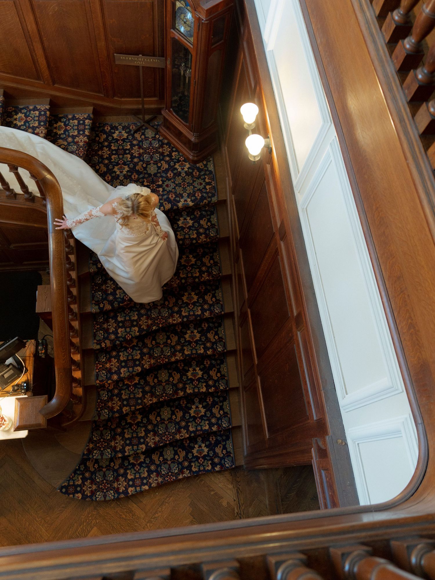 Artistic sequence showing movement down an ornate staircase with wooden paneling and floral wallpaper.