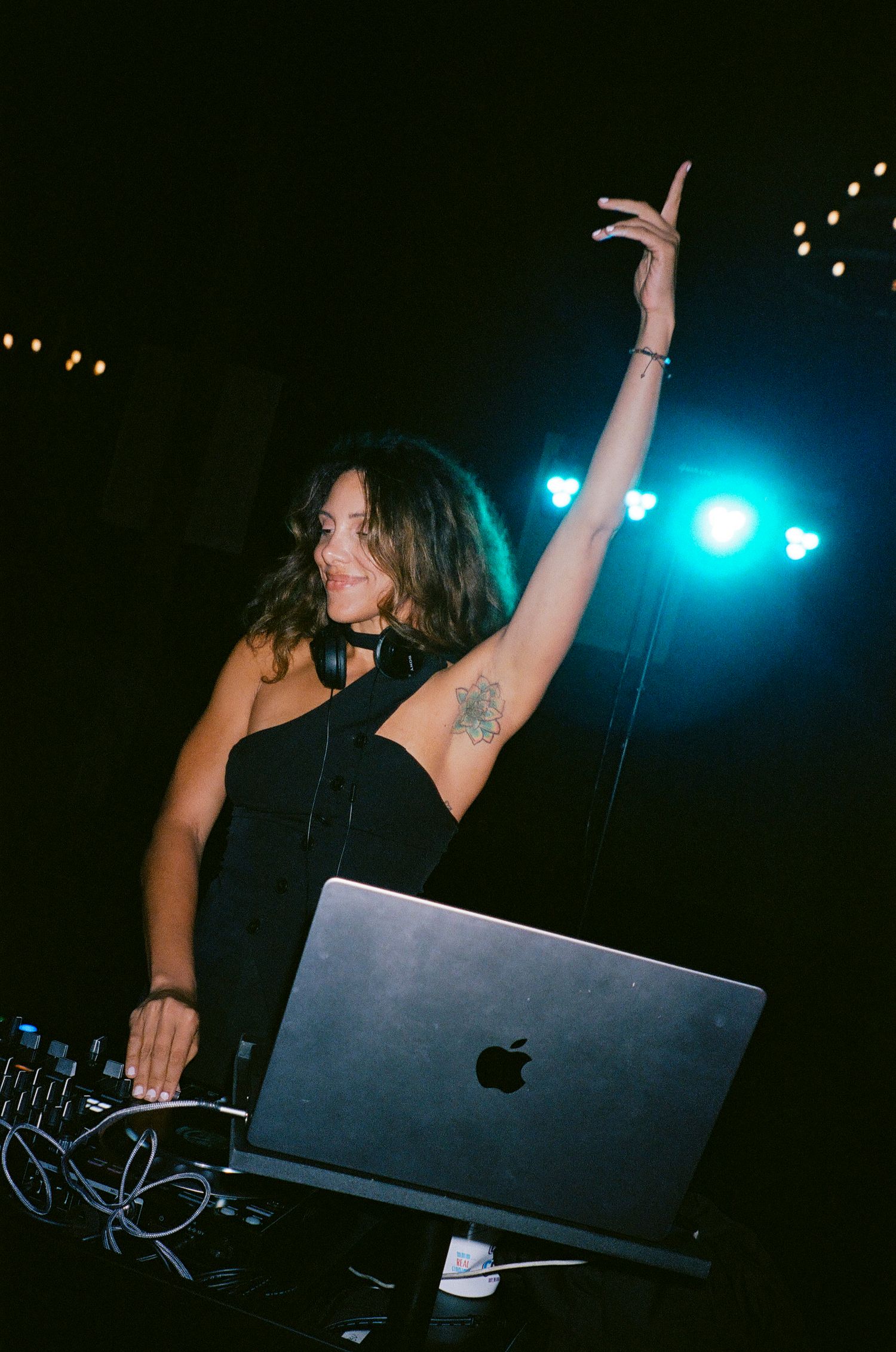 DJ performs at a nightclub with laptops and equipment under blue stage lighting.