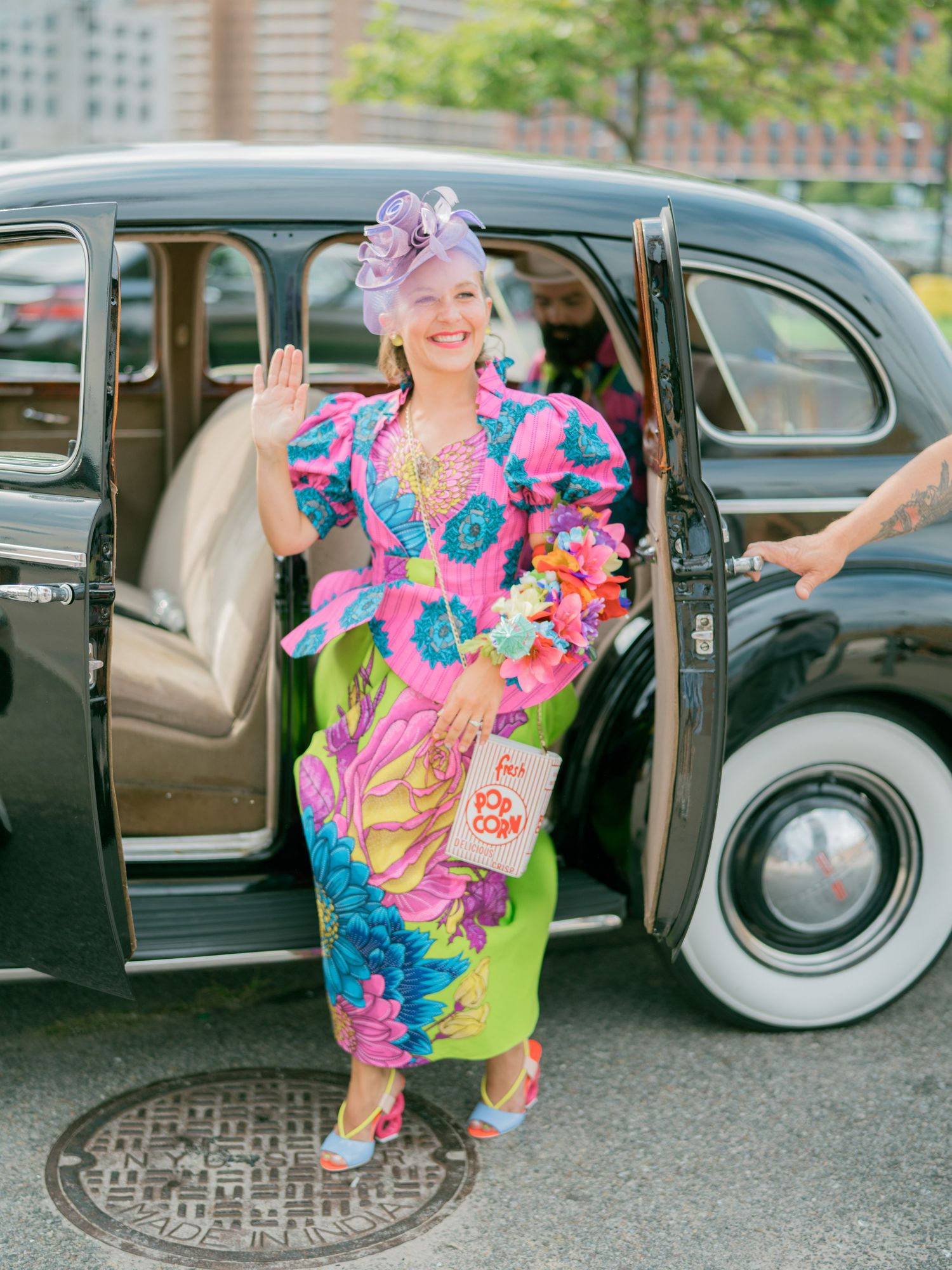 Vibrant floral dress and vintage car photoshoot featuring playful poses exiting a classic automobile.