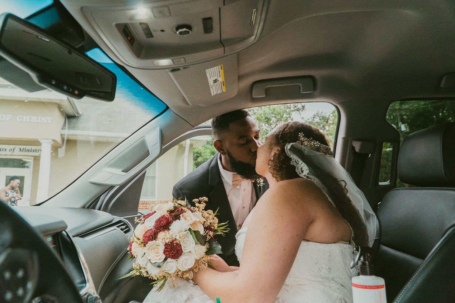 Couple exchanging kiss outdoors at Norfolk wedding ceremony