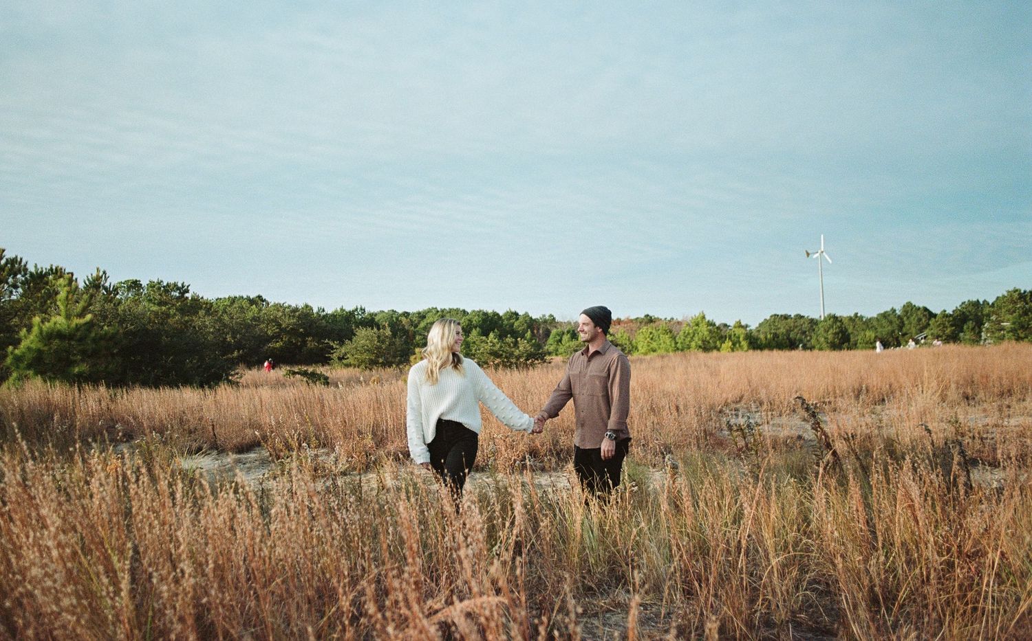 Engaged couple walking hand-in-hand at Norfolk waterfront by Norfolk photographer