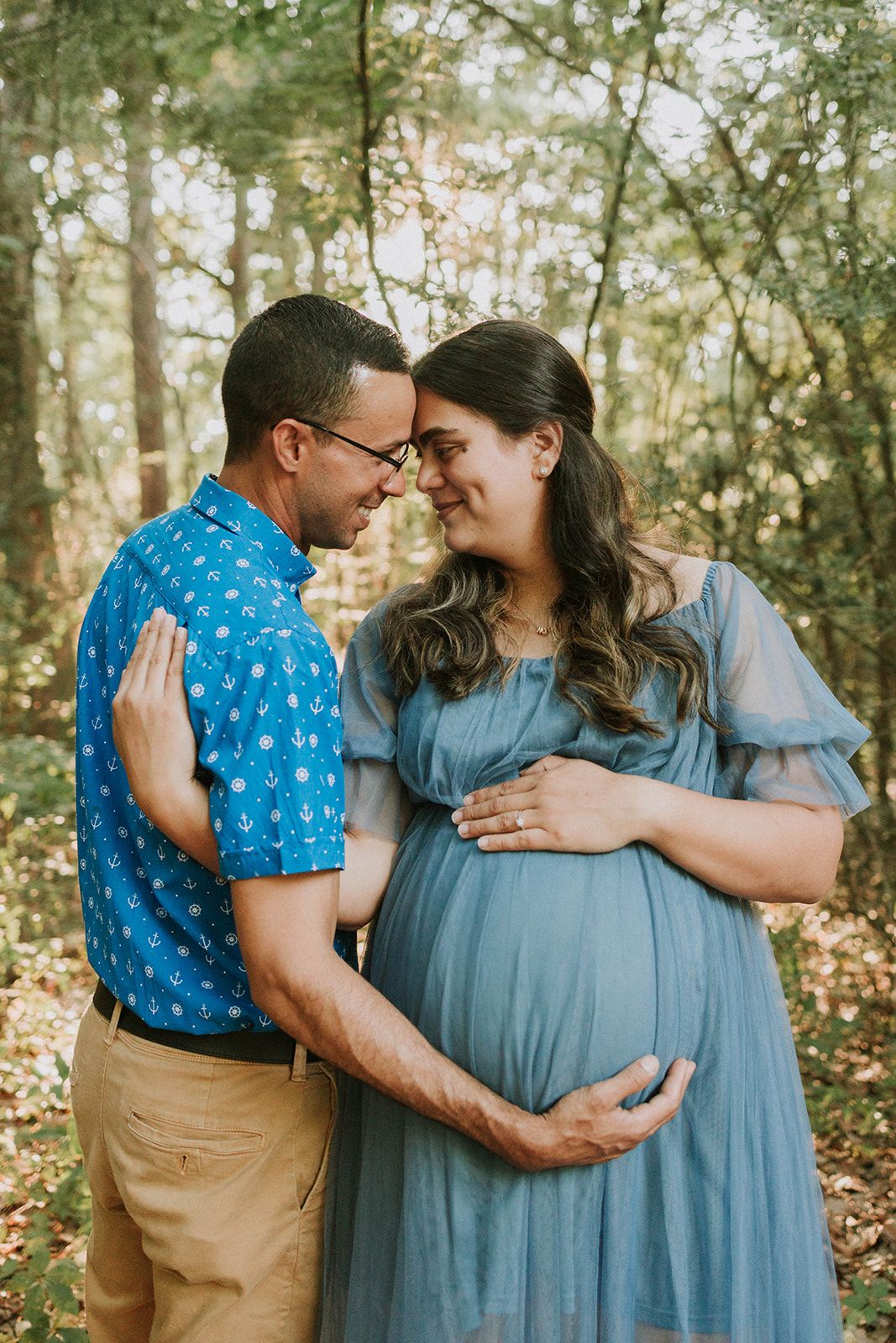 Couple shares intimate moment in forest setting.