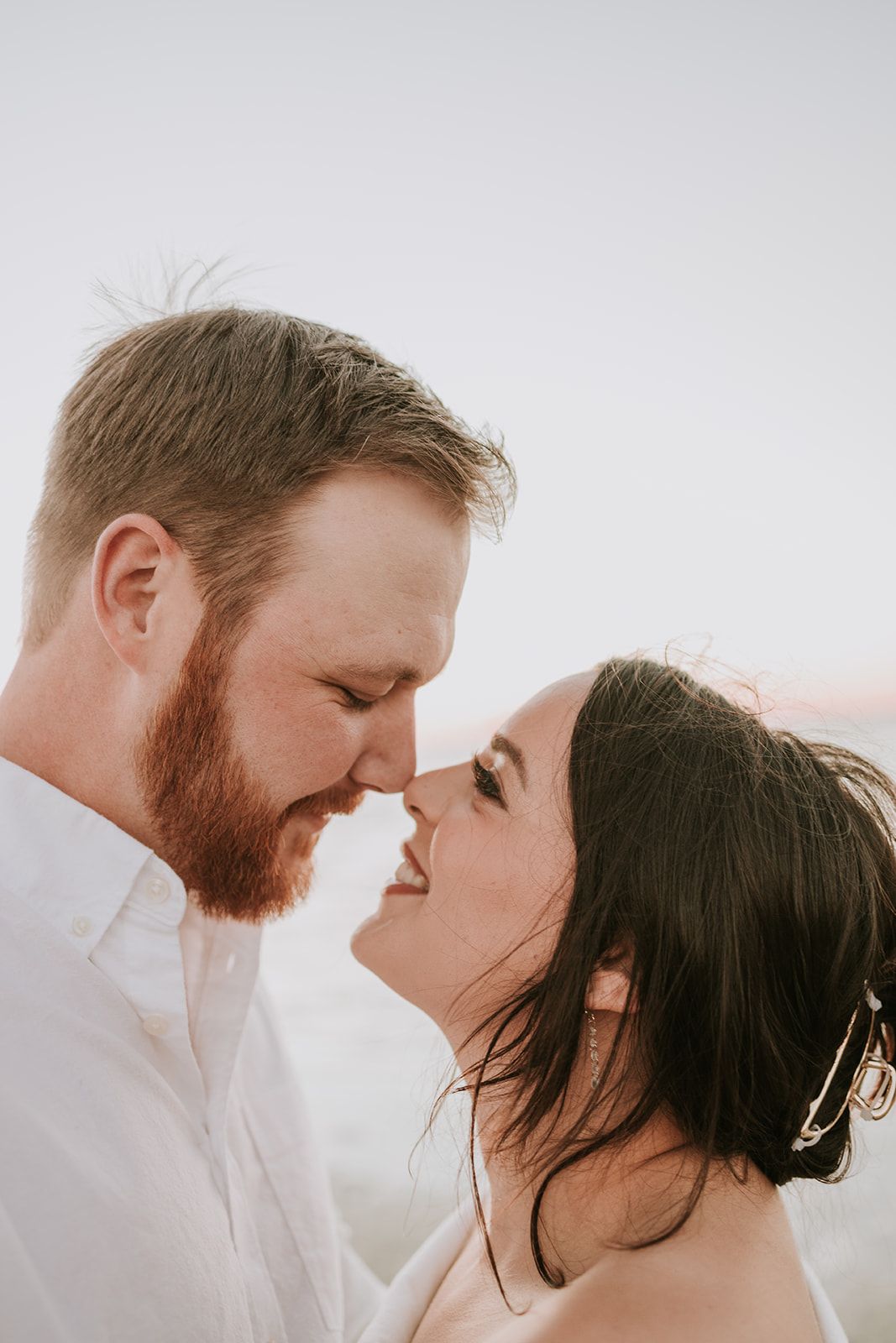 A couple shares an intimate romantic moment with their faces close together in a soft-lit portrait.