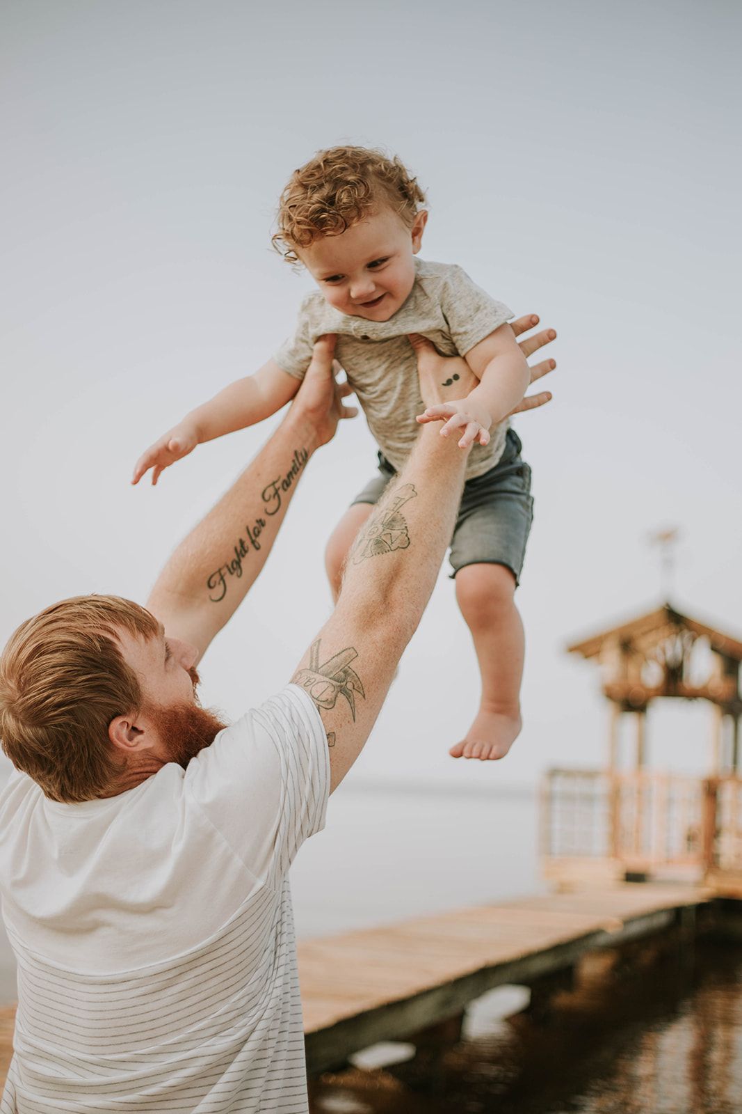 A joyful moment of play at a waterfront boardwalk with a lighthouse in the background.