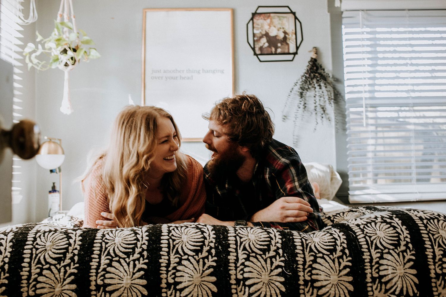 Two people and a dog lounging together on a cozy bed in natural window light.