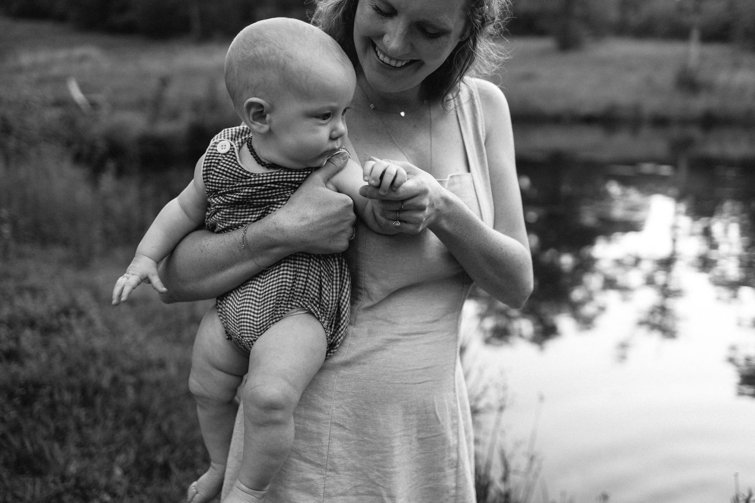 A vintage black and white photograph of parent and baby beside a reflective pond in a pastoral setting.