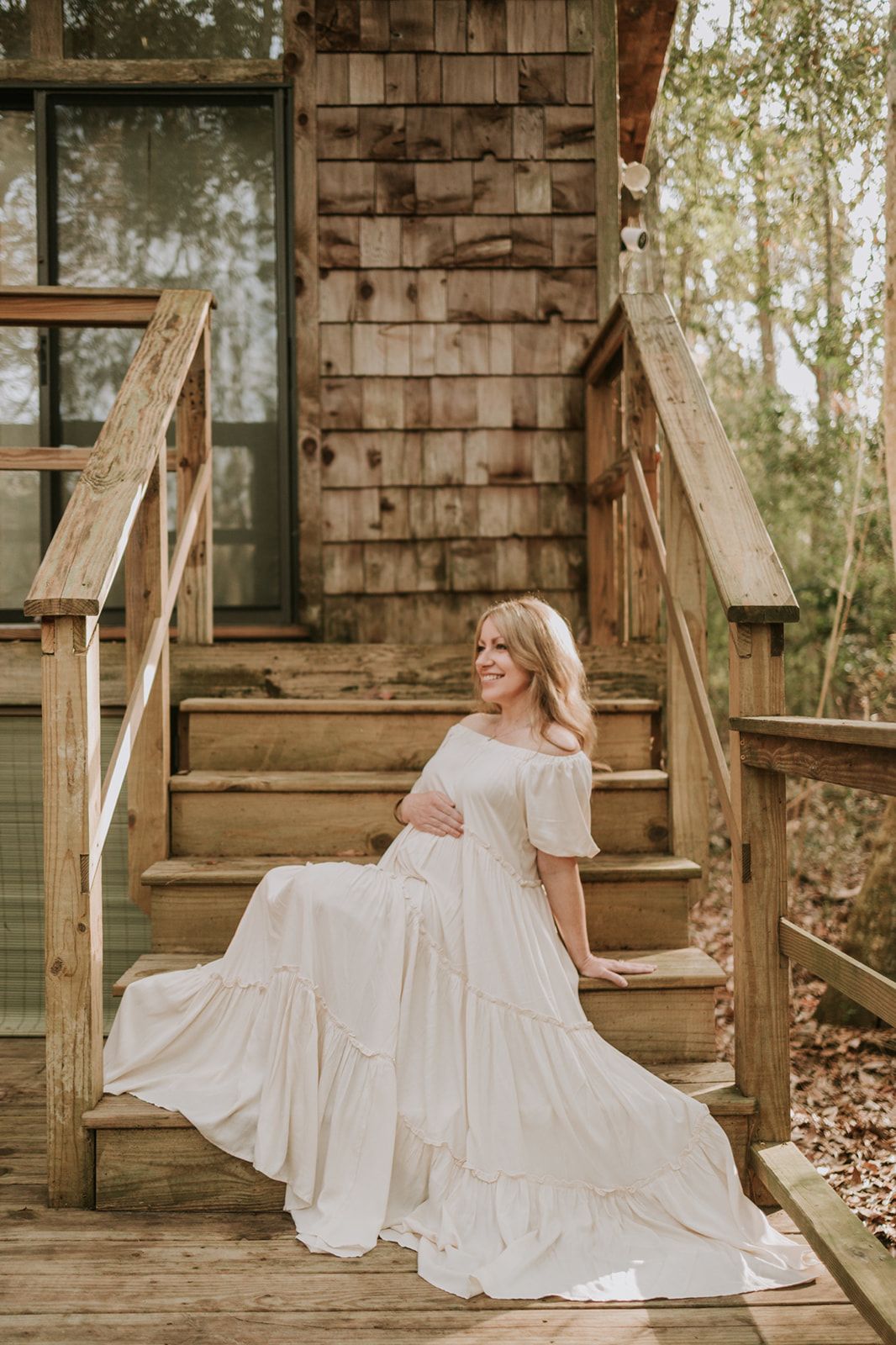Maternity photo of a flowing white dress on rustic wooden cabin steps.