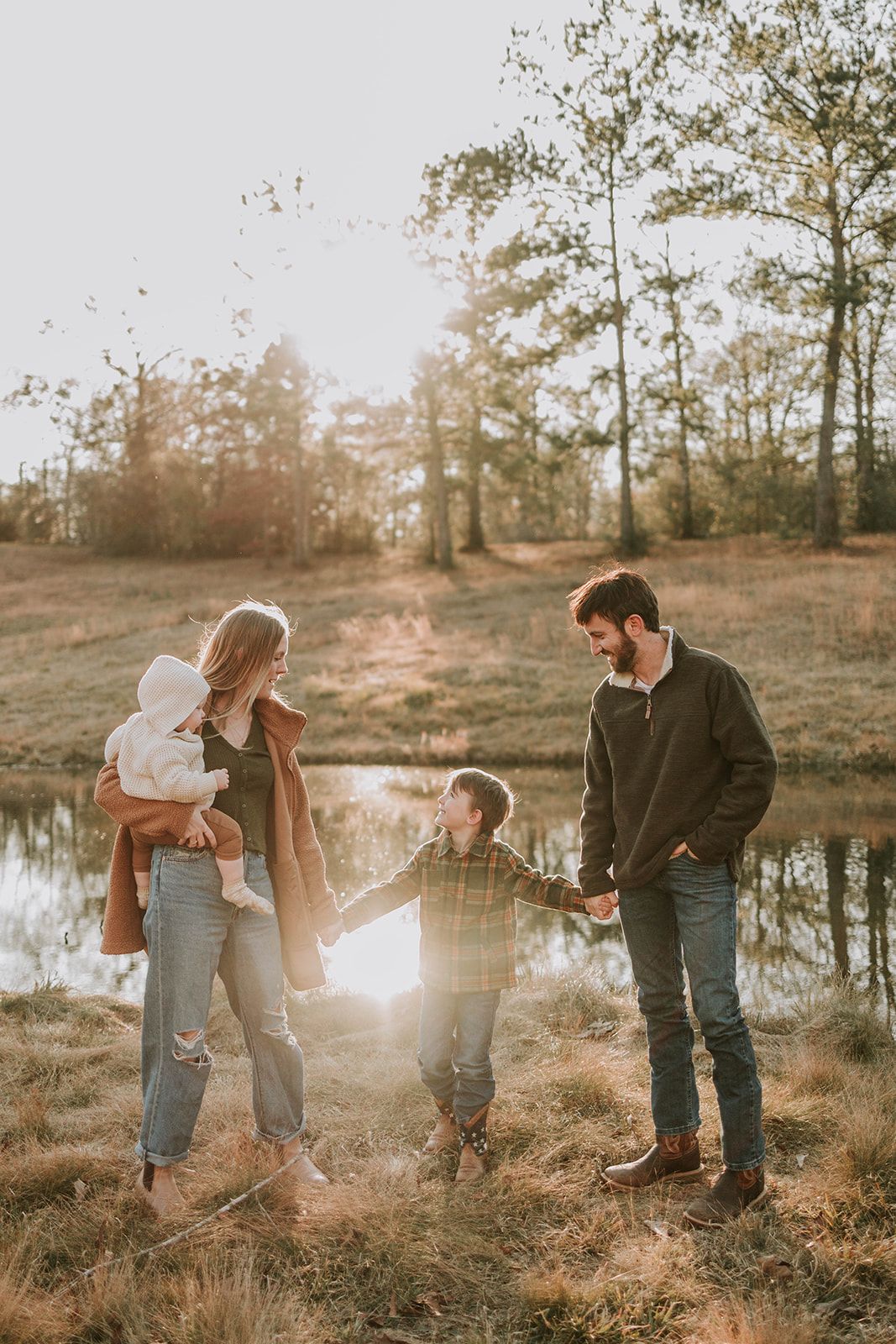 Family walking together by pond during golden hour in rustic setting.