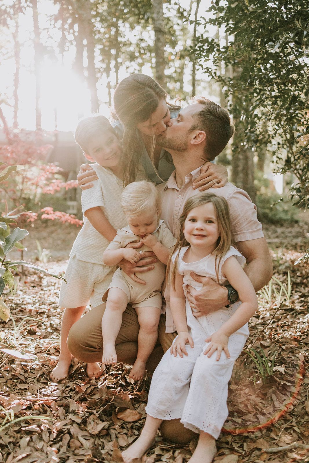 A loving family shares an intimate moment together in a sunlit wooded setting.