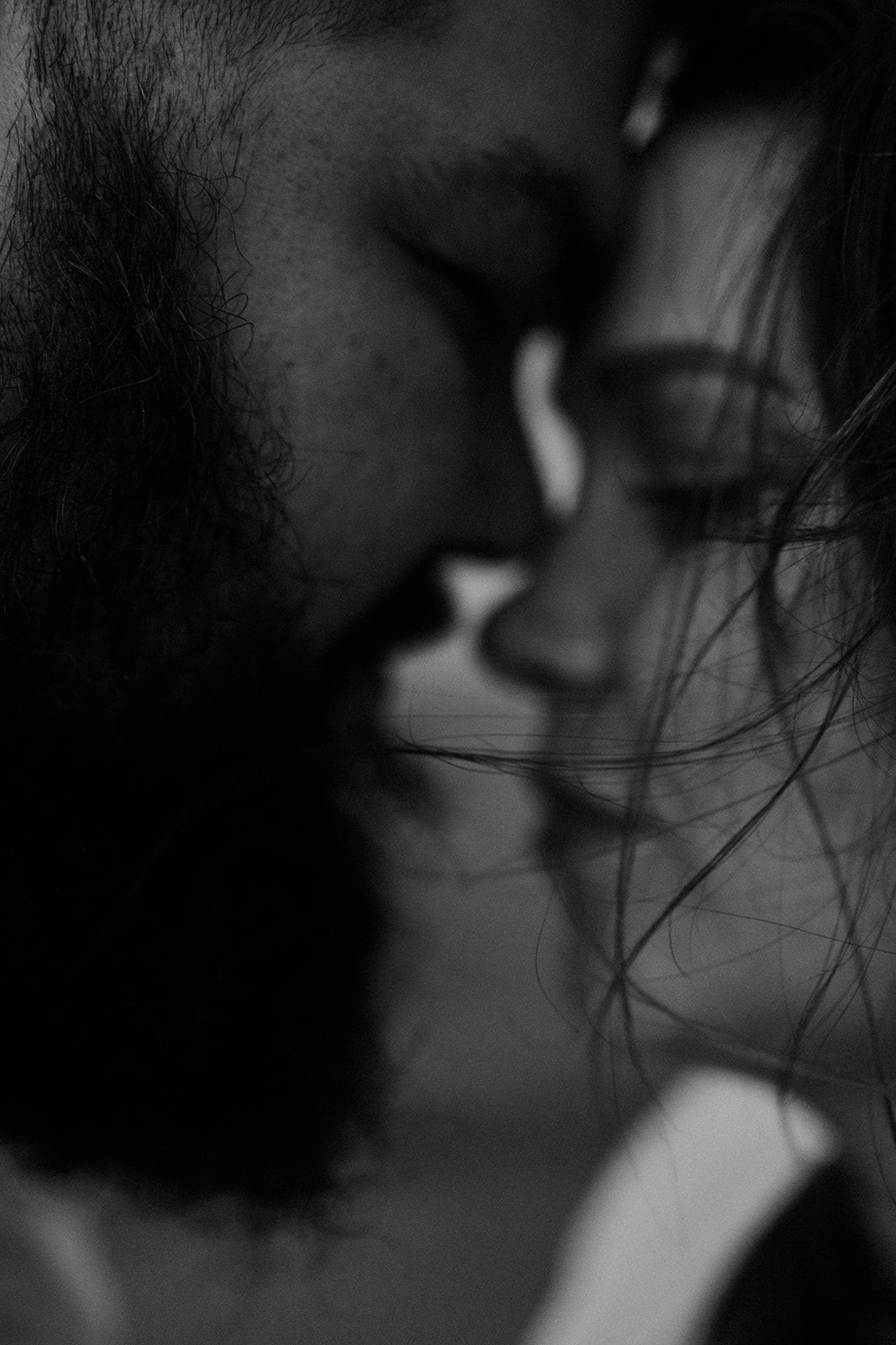 Intimate black and white close-up photo showing facial silhouettes and flowing hair in soft focus.