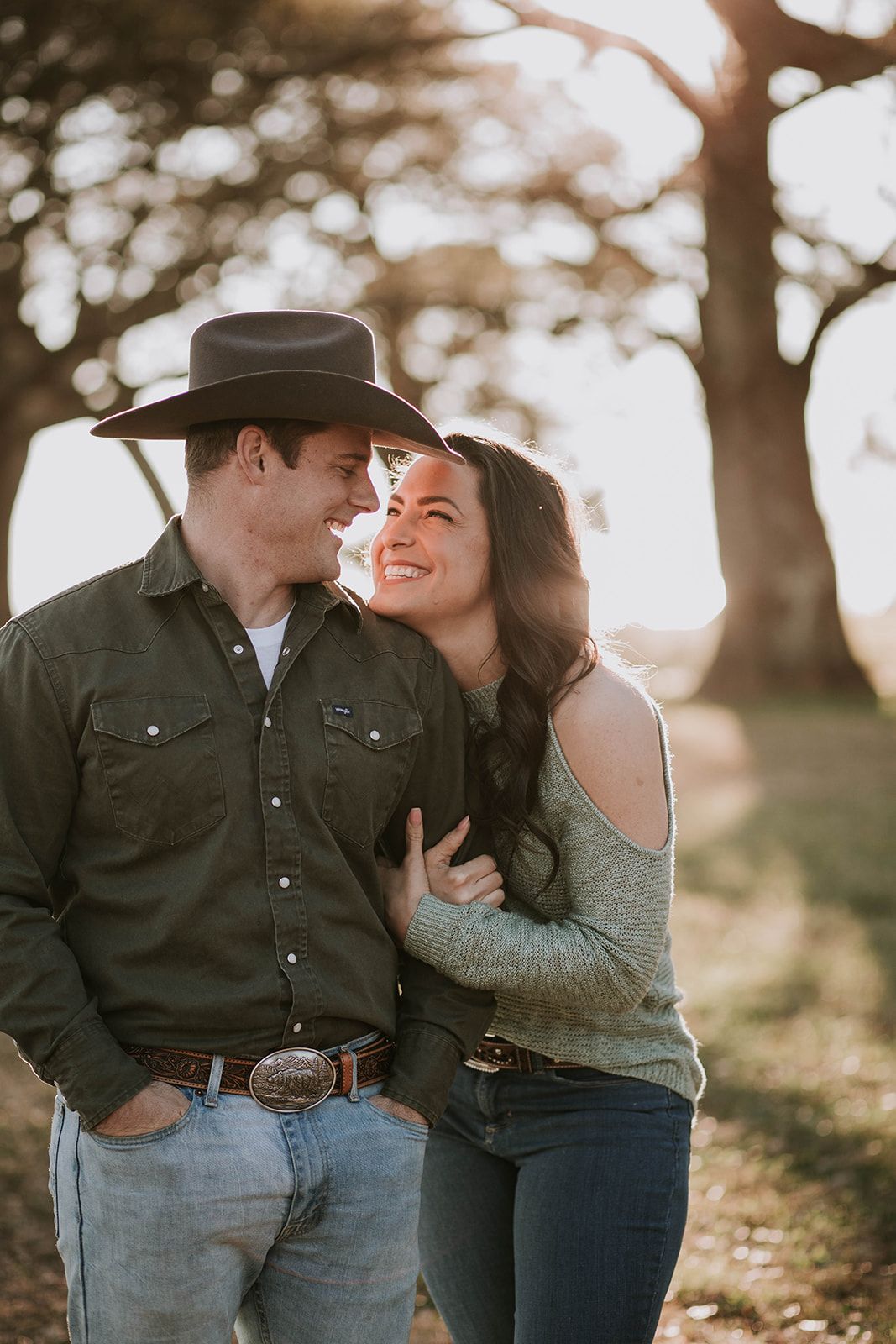 Romantic countryside portrait with couple laughing in golden sunset light.