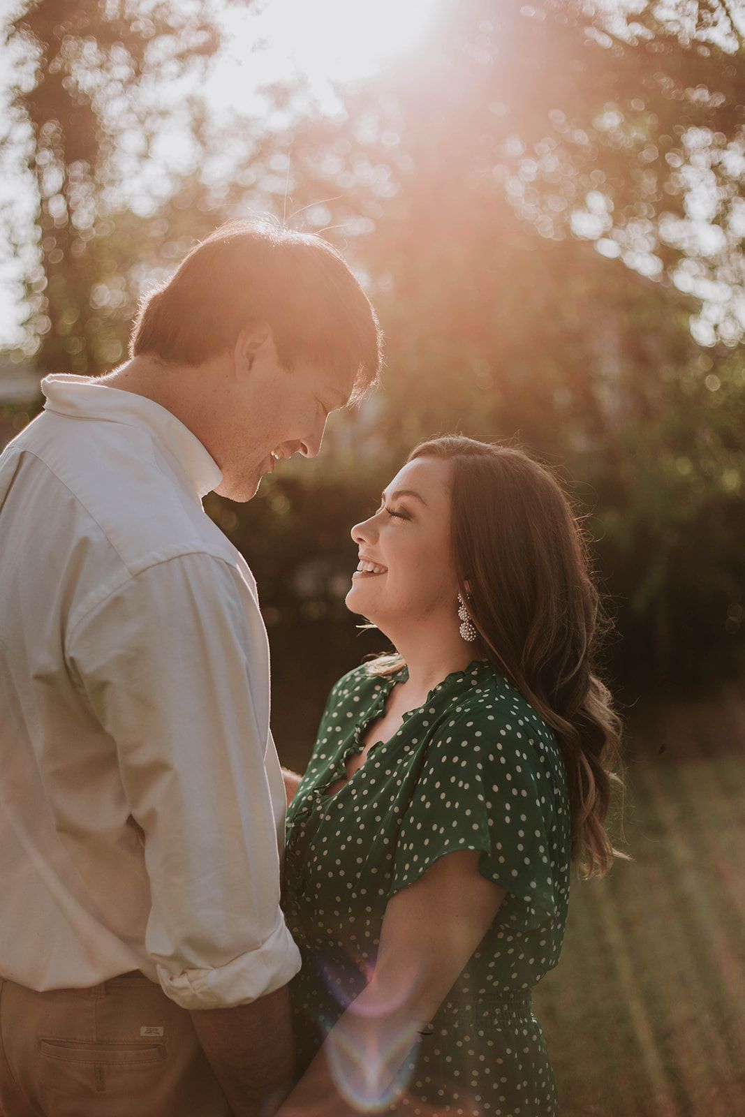 A happy couple poses in front of a vintage drugstore sign during an engagement photoshoot.