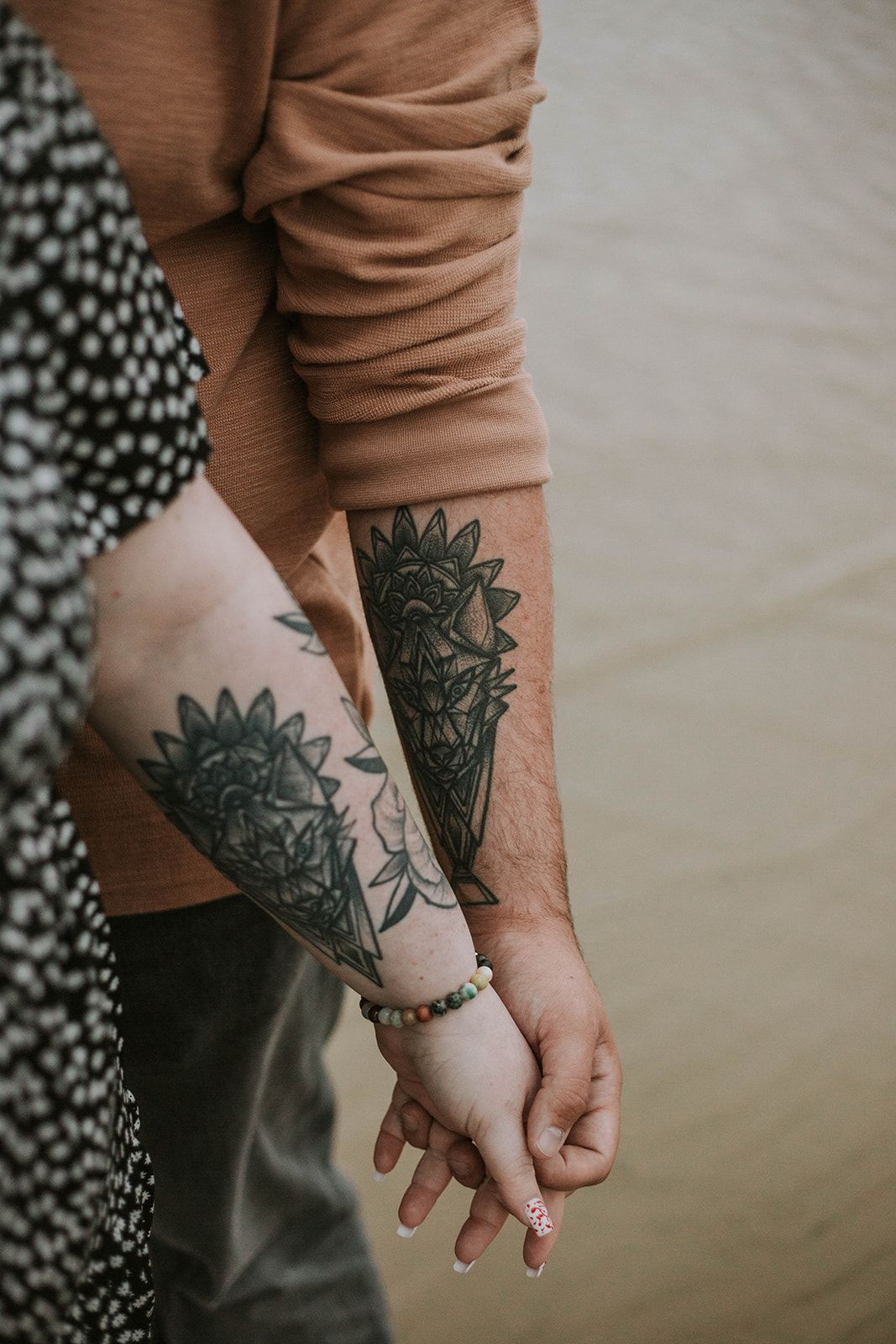 Close-up of matching floral tattoos on forearms against neutral backgrounds.